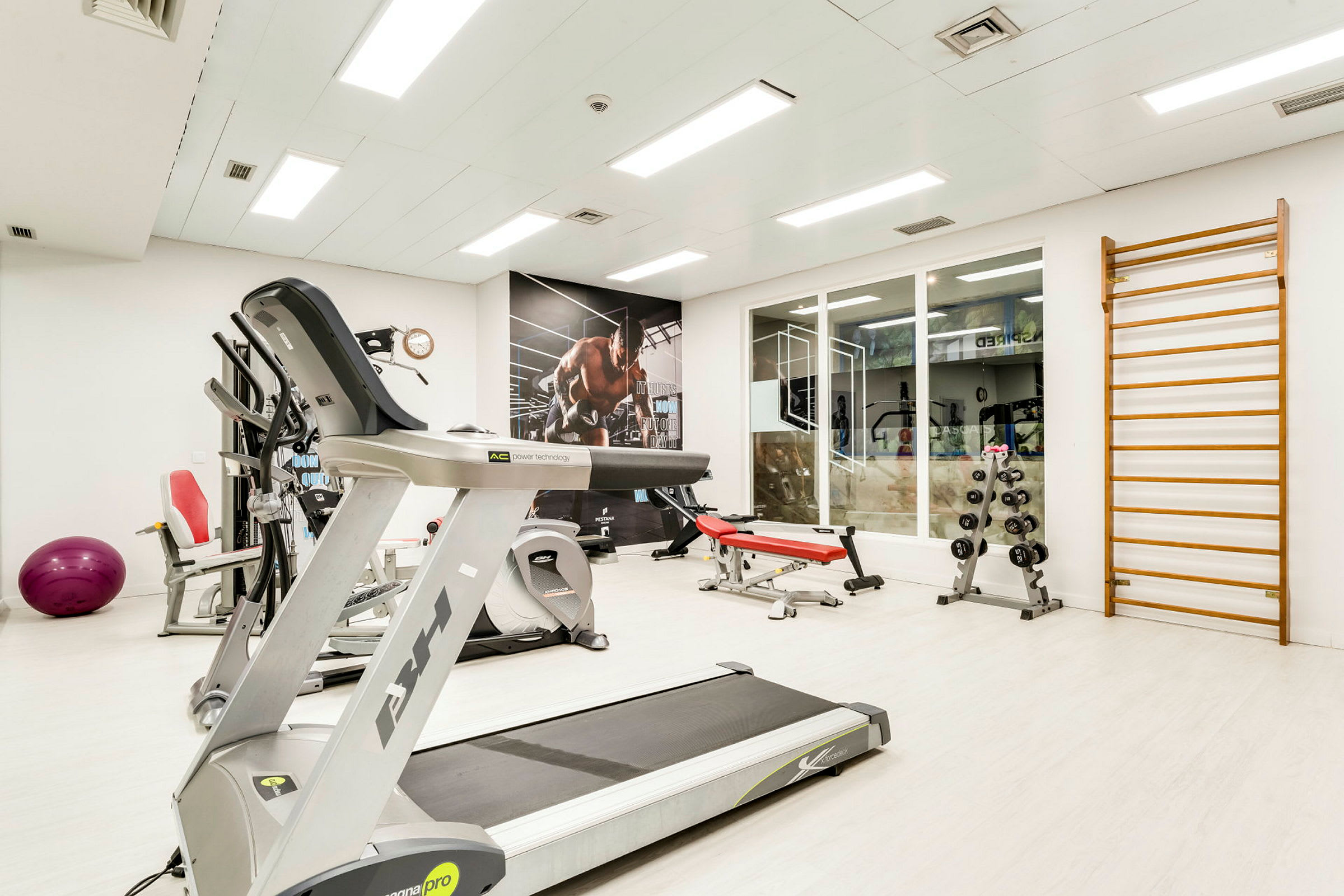 Interiören av ett gym med träningsmaskiner och träningsutrustning. (AI-genererad text)