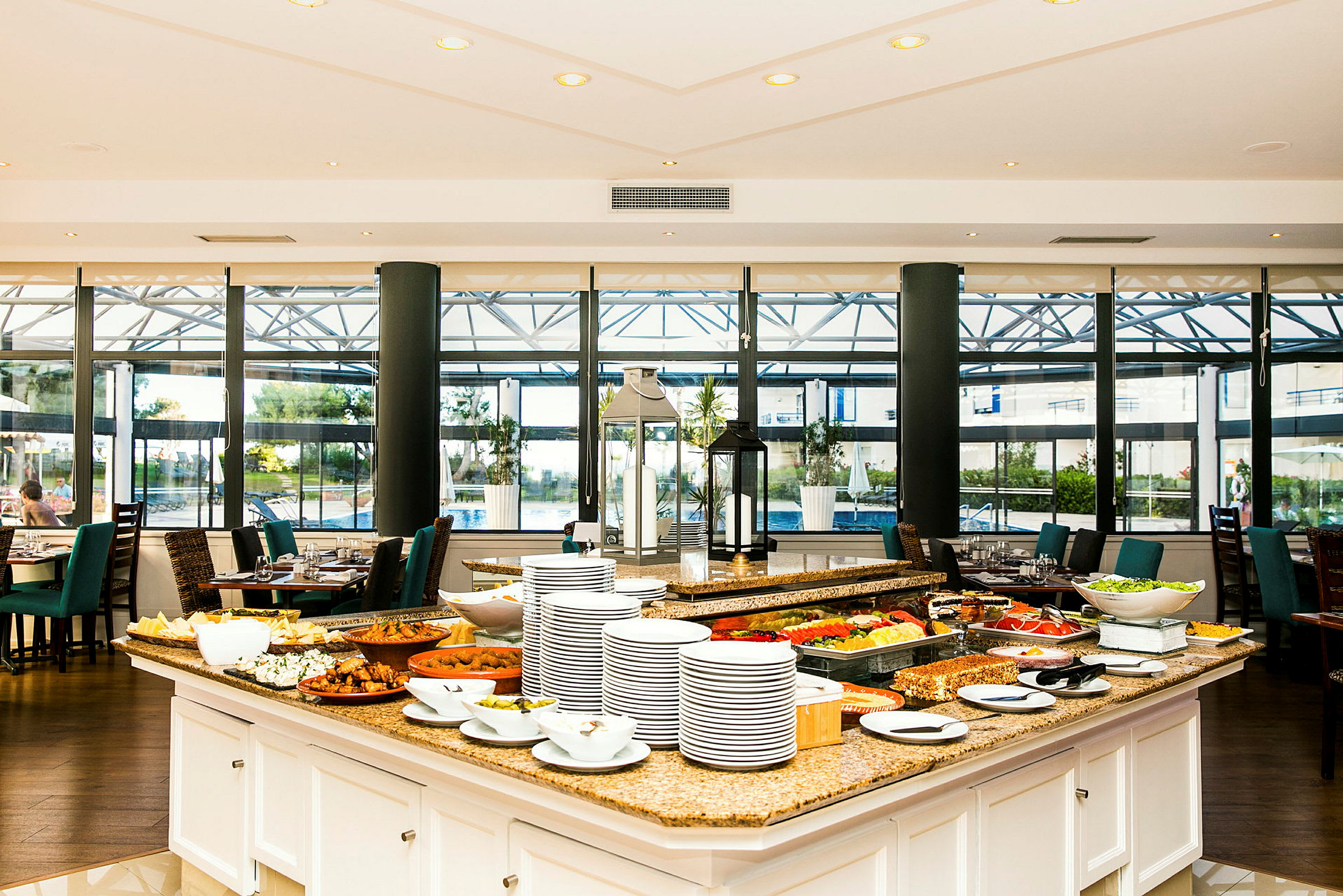 En restaurang med ett buffébord fyllt med olika rätter och tallrikar, samt sittplatser i bakgrunden. (AI-genererad text)