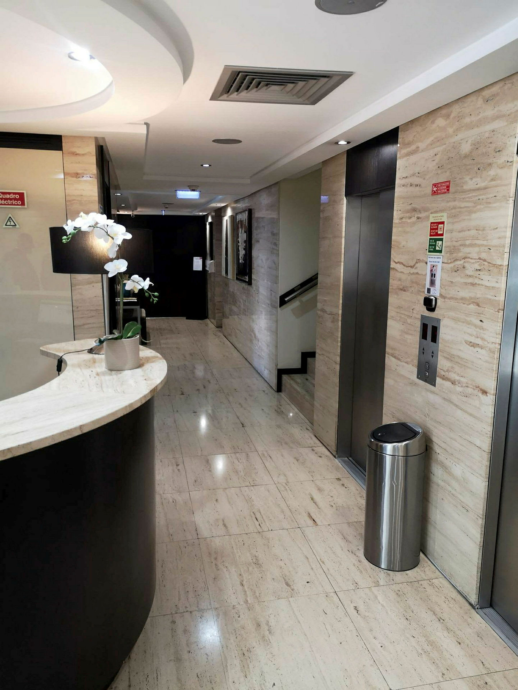 En modern hotellkorridor med hiss och concierge-reception. (AI-genererad text)
