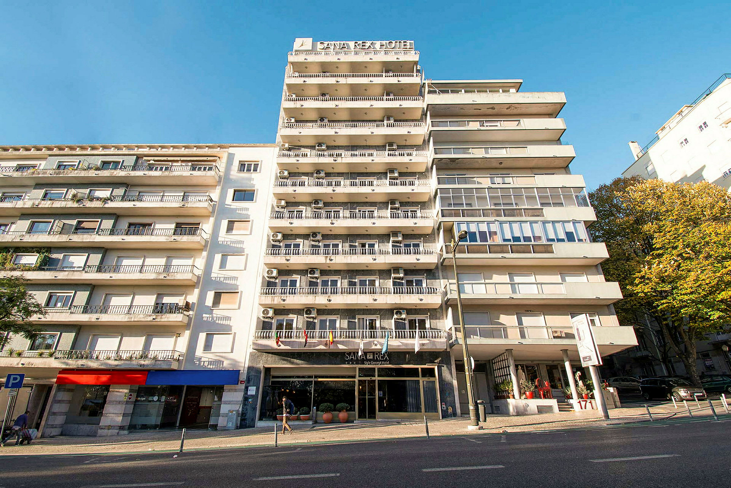 Flerbostadshus med hotellskylt och balkonger under en klarblå himmel. (AI-genererad text)