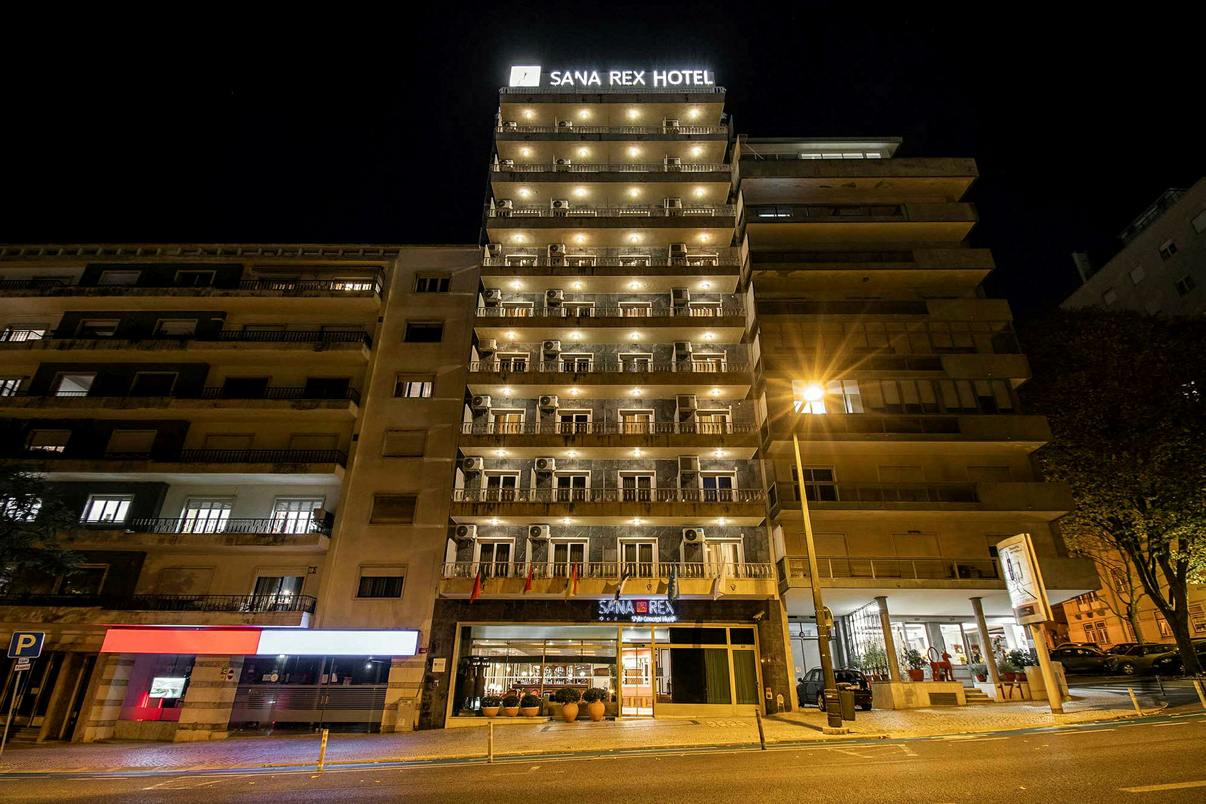 Bild av hotellet Sana Rex Hotel på natten, med fasaden upplyst. (AI-genererad text)