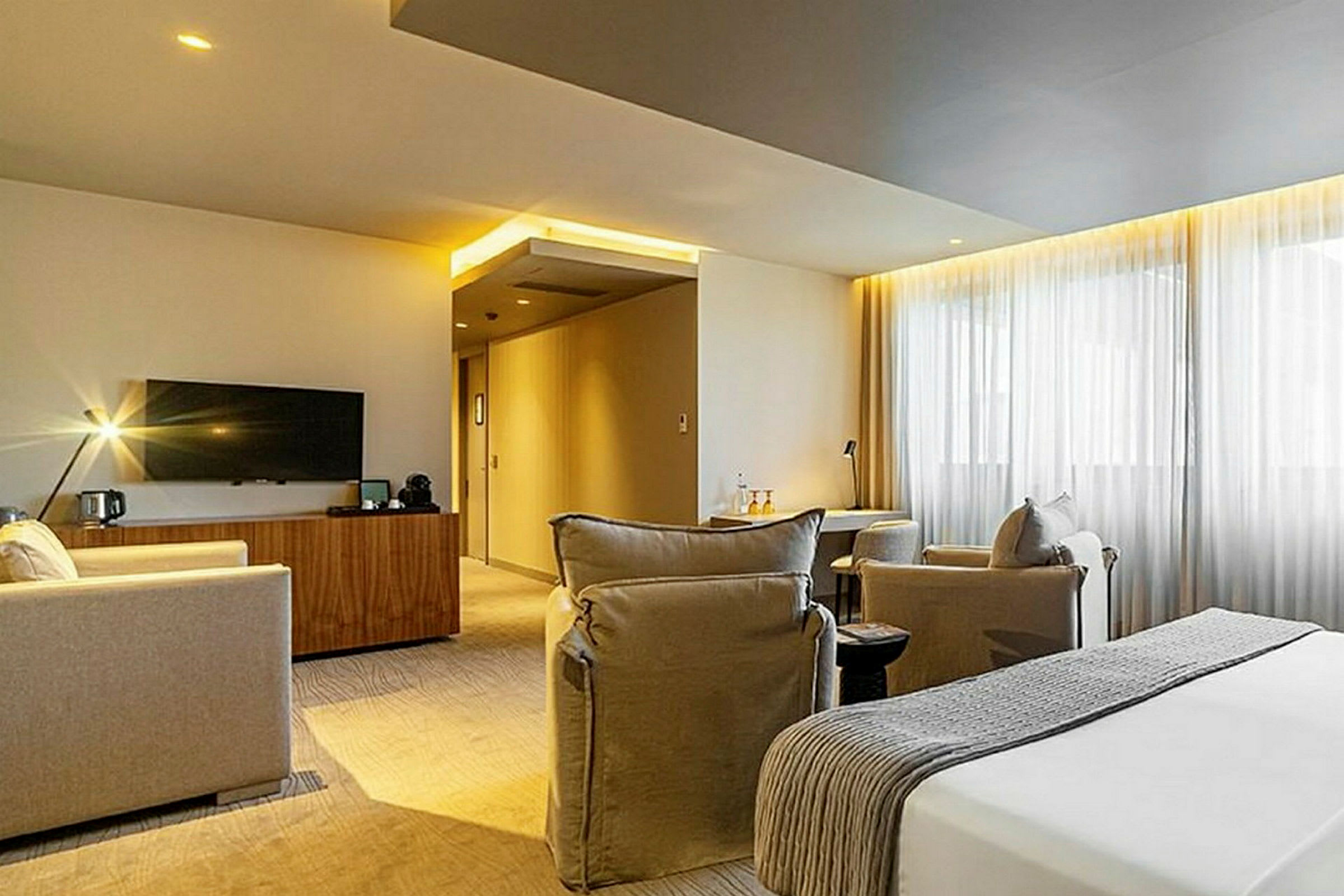 Ett modernt hotellrum med en sittgrupp, en säng och en TV. (AI-genererad text)
