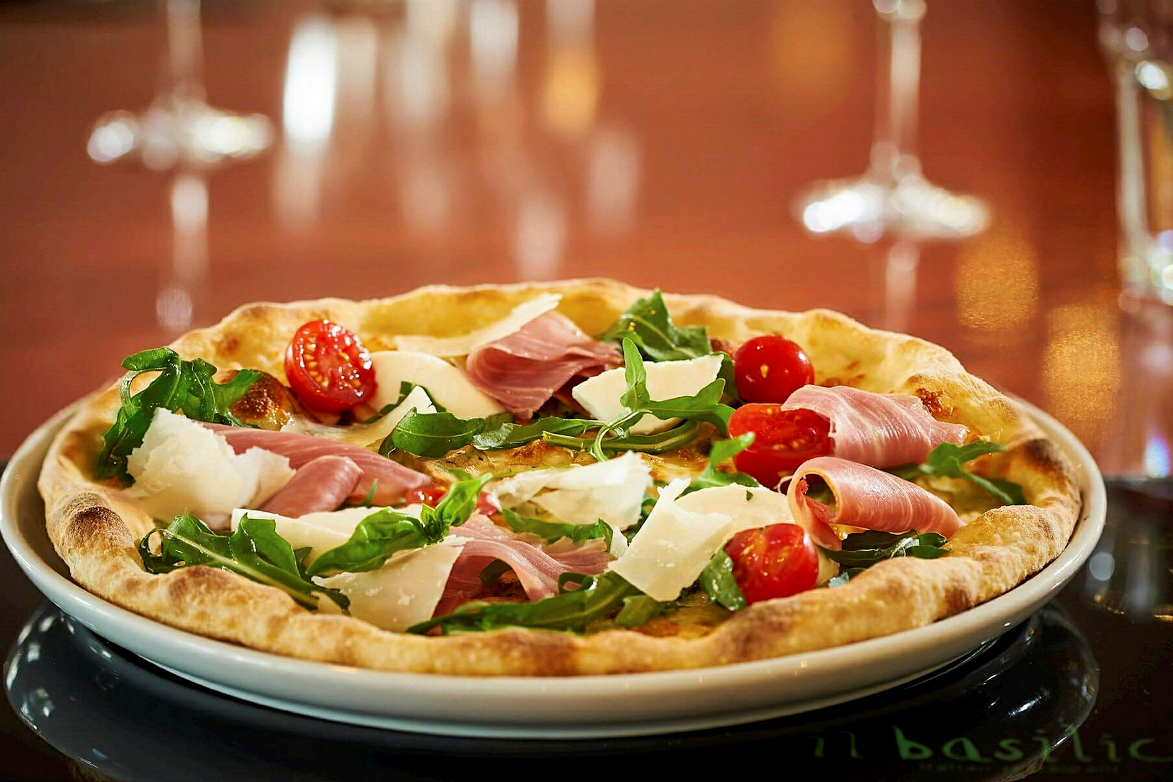 En pizza med körsbärstomater, ruccola, parmesan och skinka. (AI-genererad text)