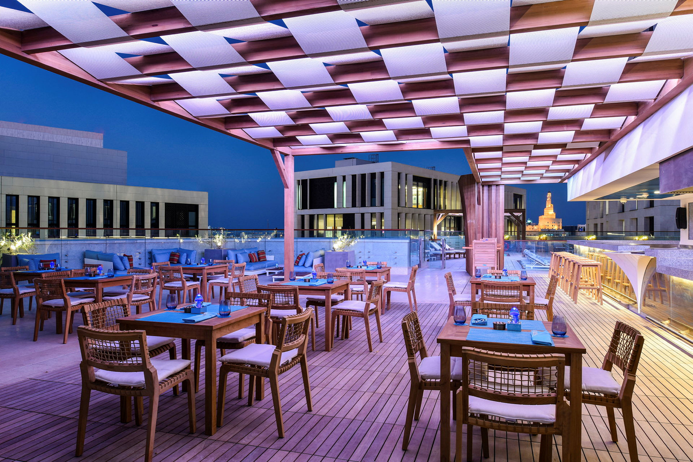 Takbar med sittplatser och bord på en terrass med utsikt över stadens arkitektur. (AI-genererad text)