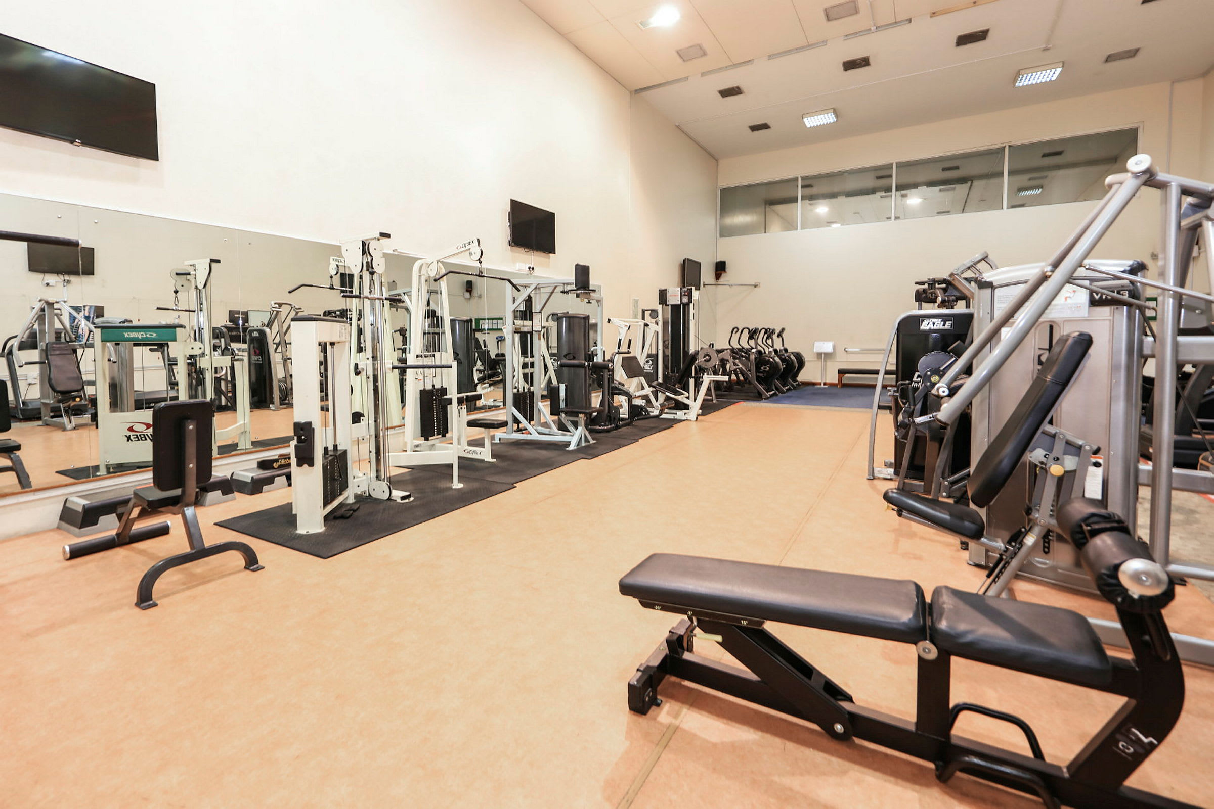 Ett gym med olika träningsmaskiner och spegelvägg. (AI-genererad text)