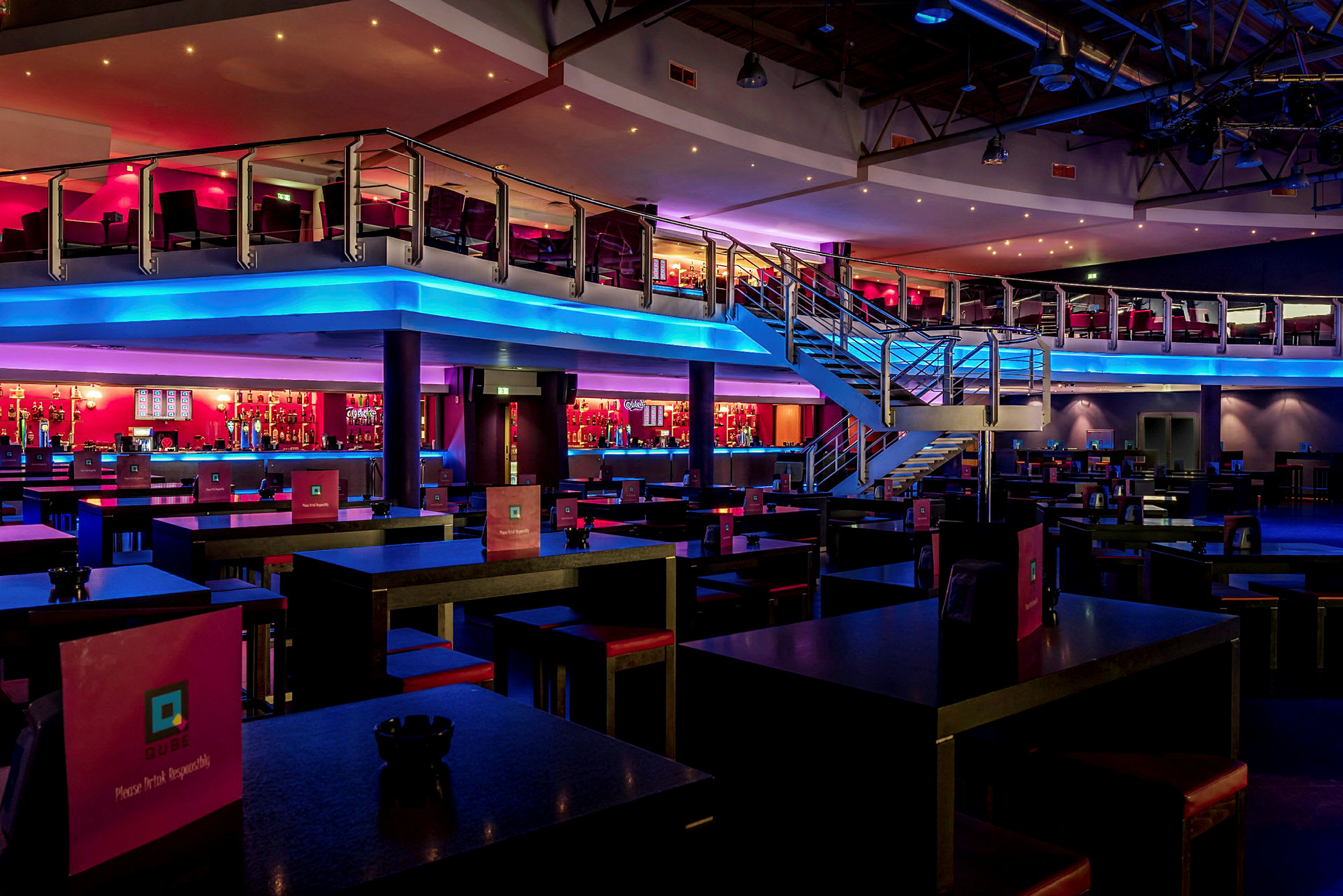 En restaurang eller nattklubb med en modern inredning, två våningar och färgglad belysning. (AI-genererad text)