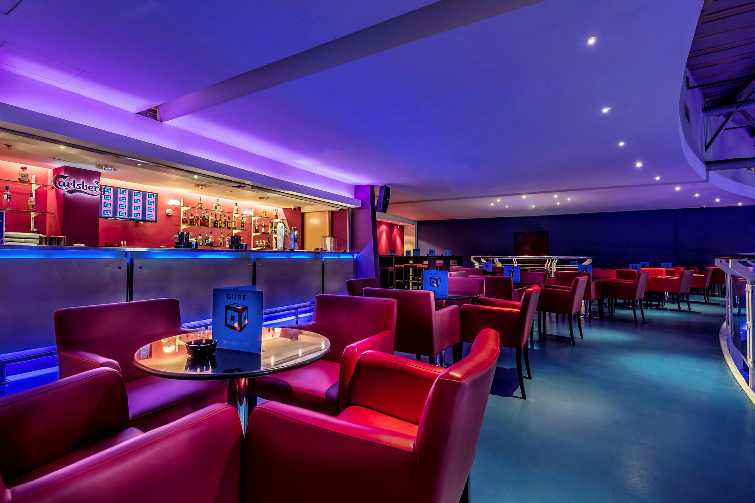 En modern bar med röd sittgrupp och stämningsbelysning. (AI-genererad text)