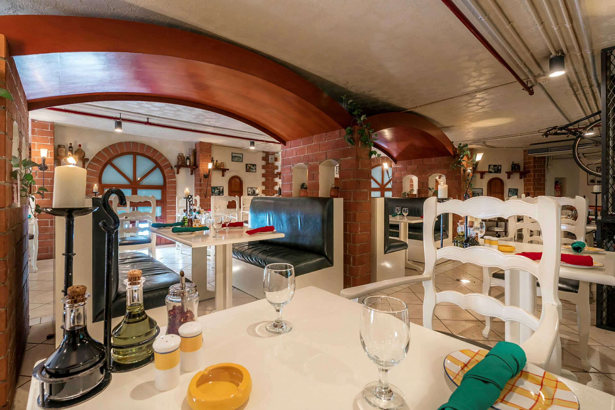 En interiör av en restaurang med vita bord, stolar och tegelstensväggar. (AI-genererad text)