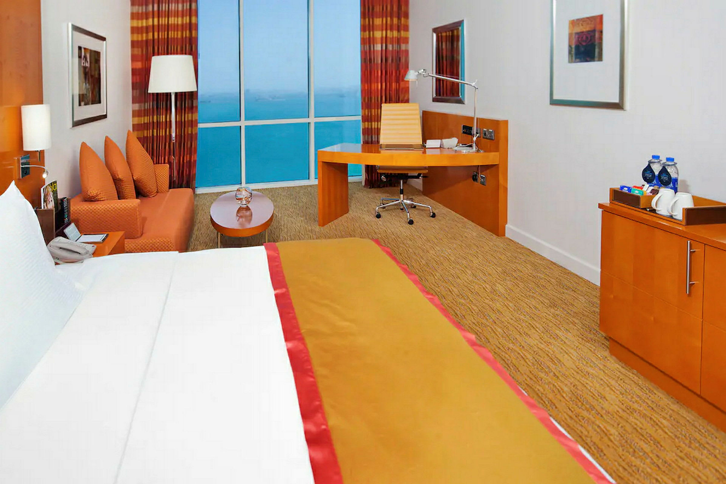 Ett hotellrum med en säng, en soffa, ett skrivbord och ett stort fönster med utsikt. (AI-genererad text)