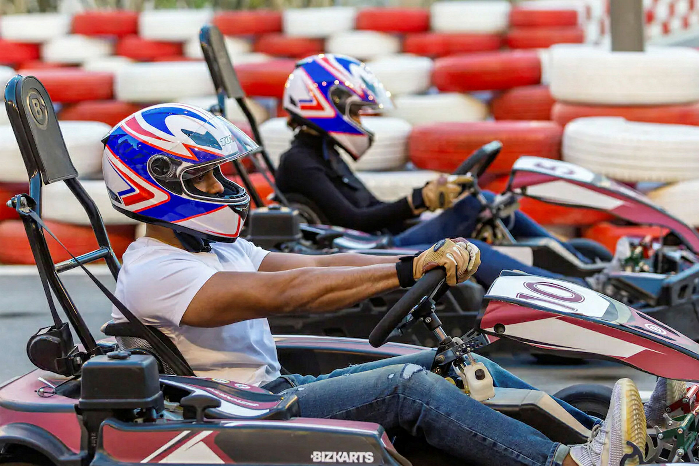 Två personer kör gokart på en bana omgiven av staplade däck. (AI-genererad text)