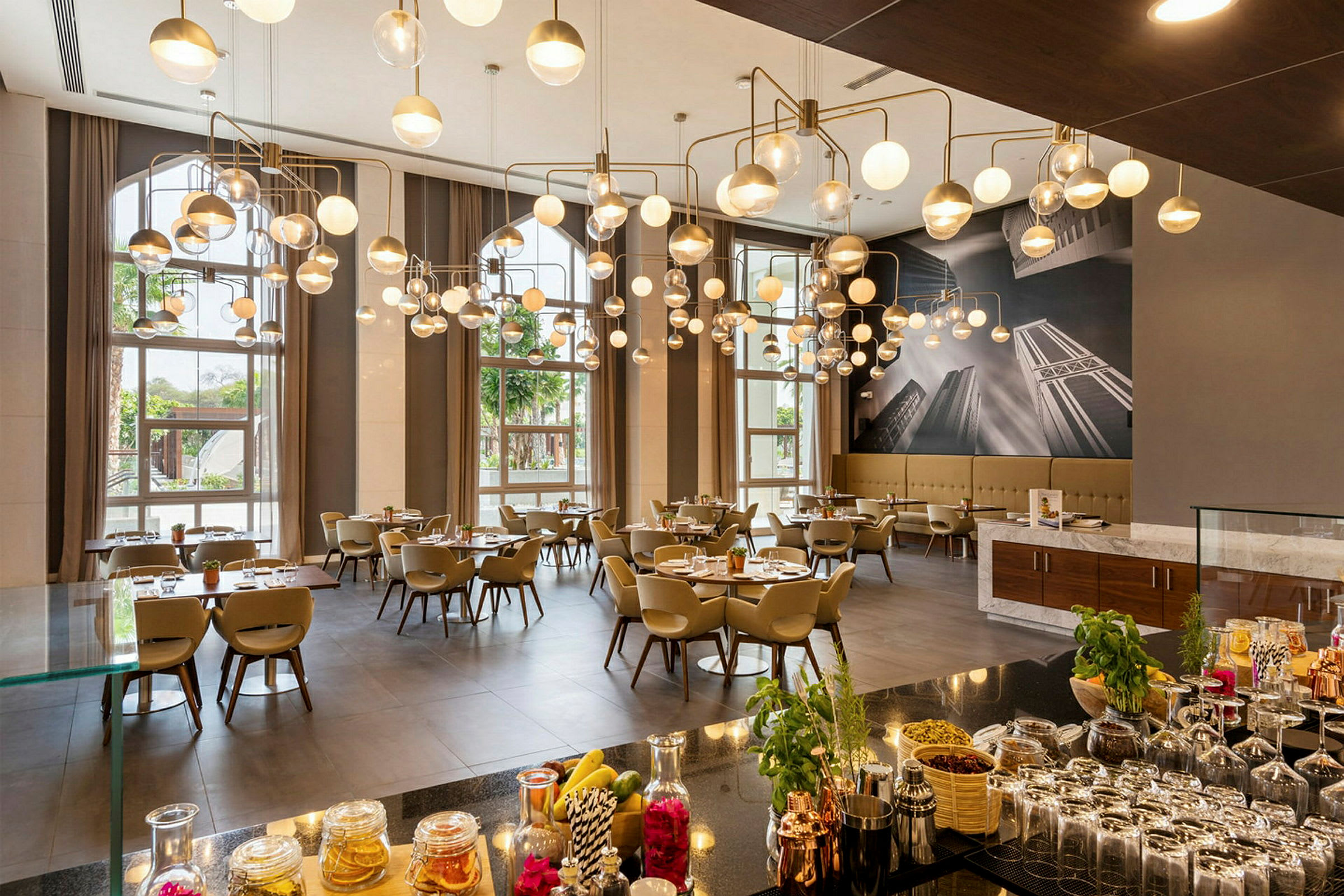 En elegant restaurang med moderna hängande lampor, dukade bord och stora fönster som släpper in naturligt ljus. (AI-genererad text)