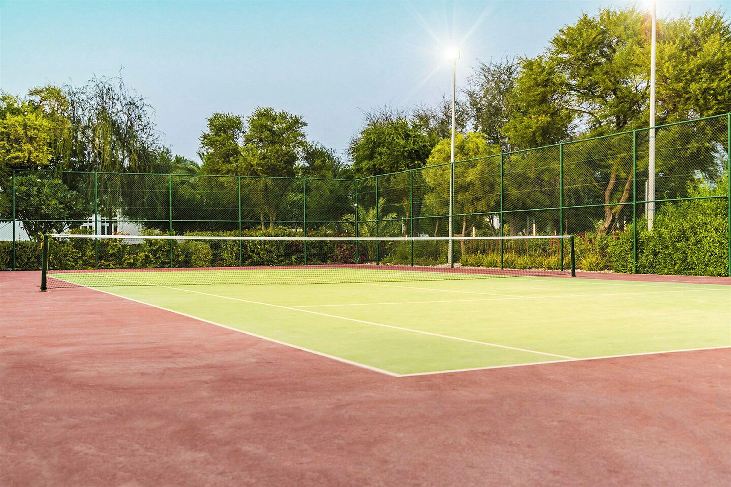 En tom tennisplan med nät och omgivande grönska. (AI-genererad text)
