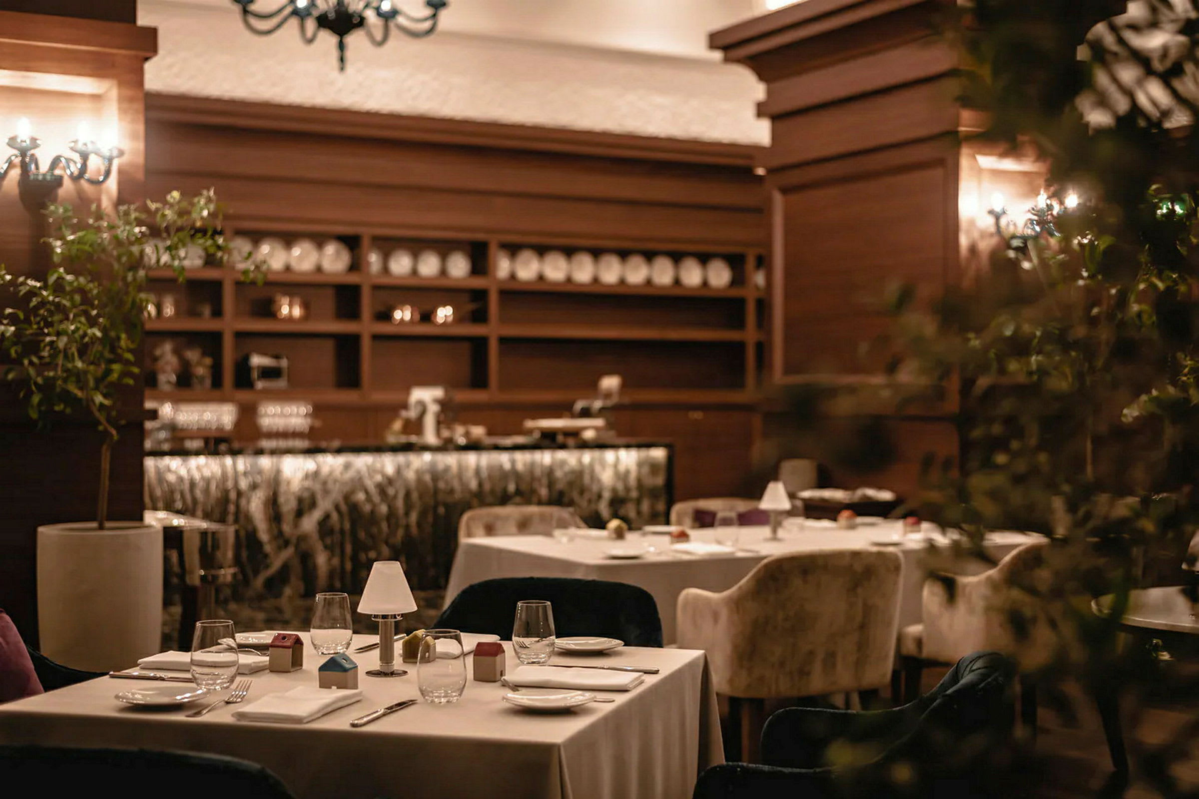 Ett restauranginteriör med dukade bord och bekväma stolar, omgiven av varm belysning och trädekorationer. (AI-genererad text)