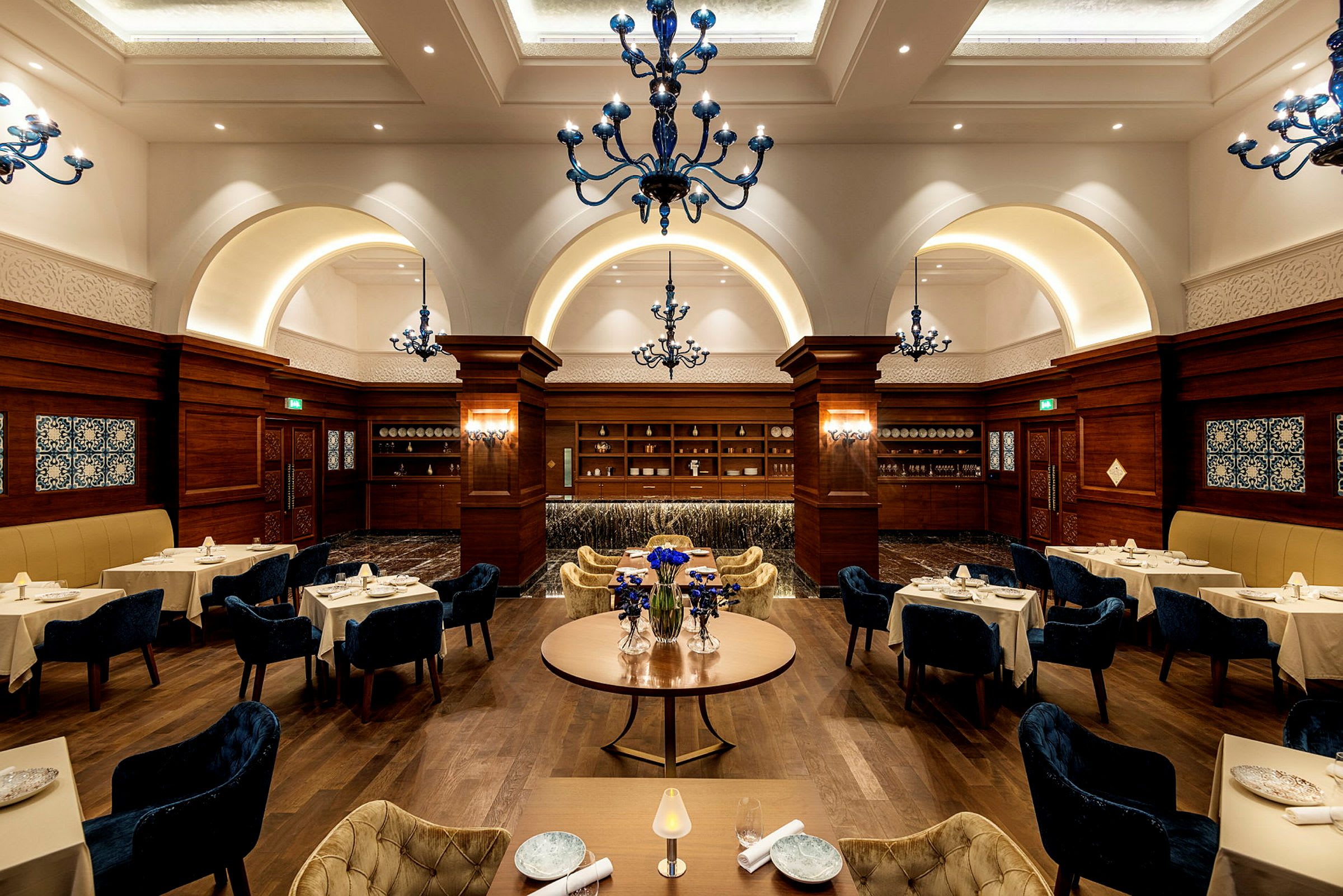 Interiör av en elegant restaurang med dukade bord och dekorerade blå takkronor. (AI-genererad text)