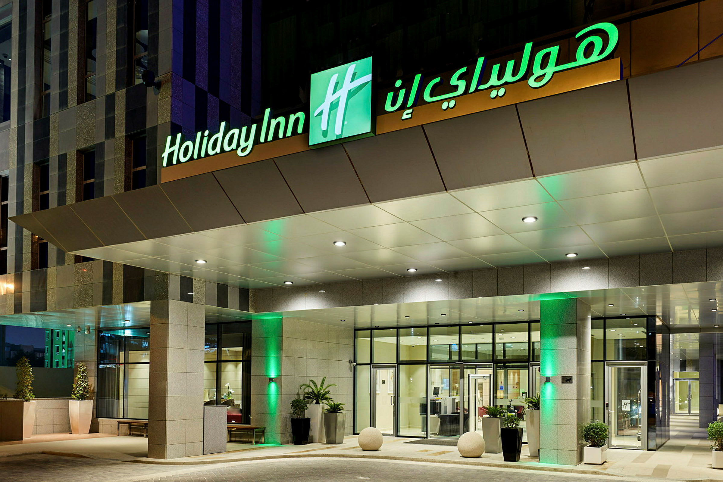 Entrén till ett hotell med skylten 'Holiday Inn' som är upplyst. (AI-genererad text)