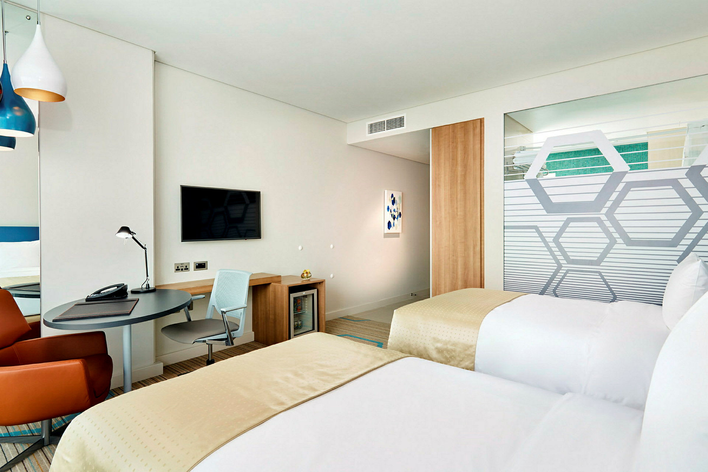 Hotelrum med två enkelsängar, skrivbord och vägg-TV. (AI-genererad text)