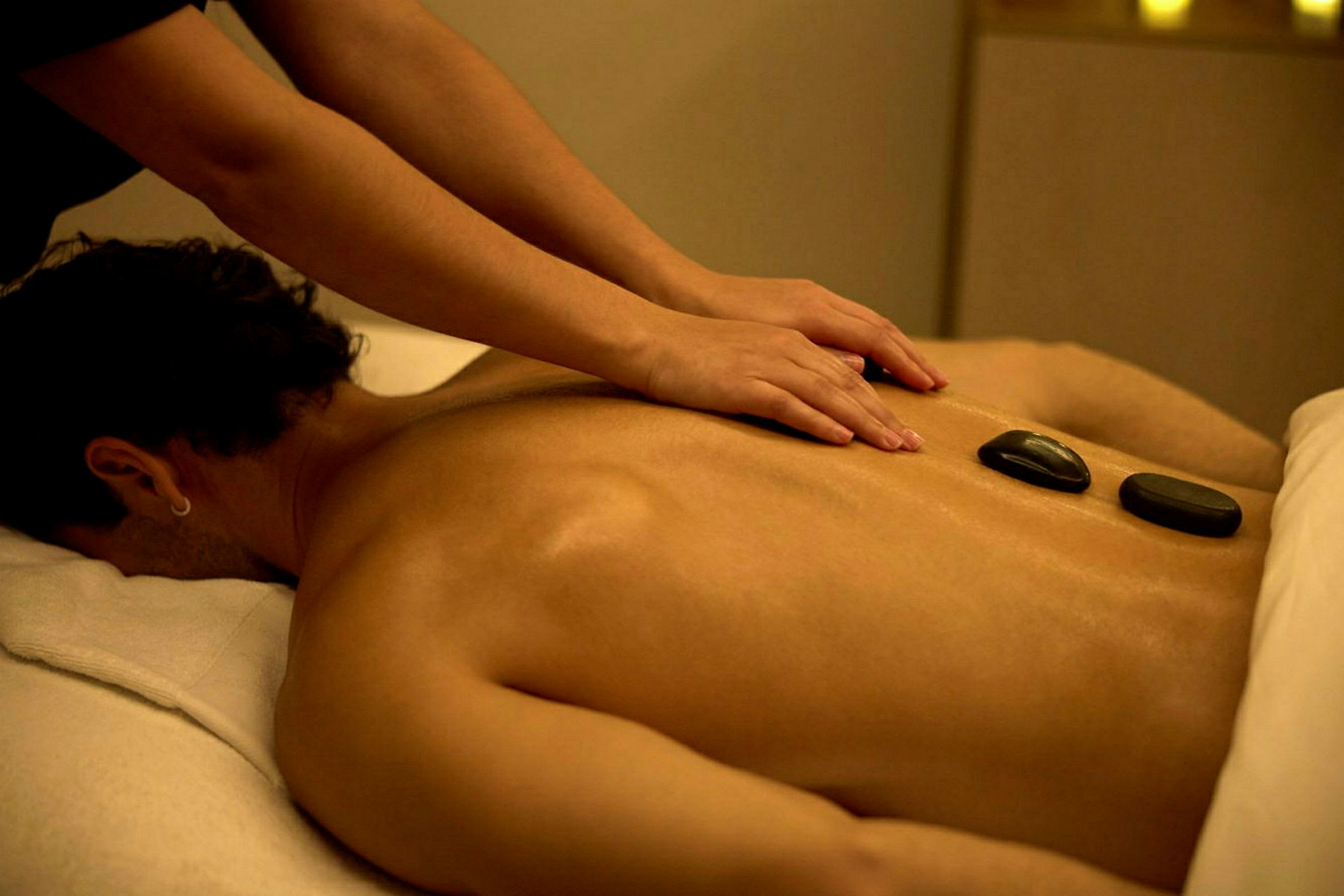 En person får massage på ryggen med två heta stenar placerade. (AI-genererad text)