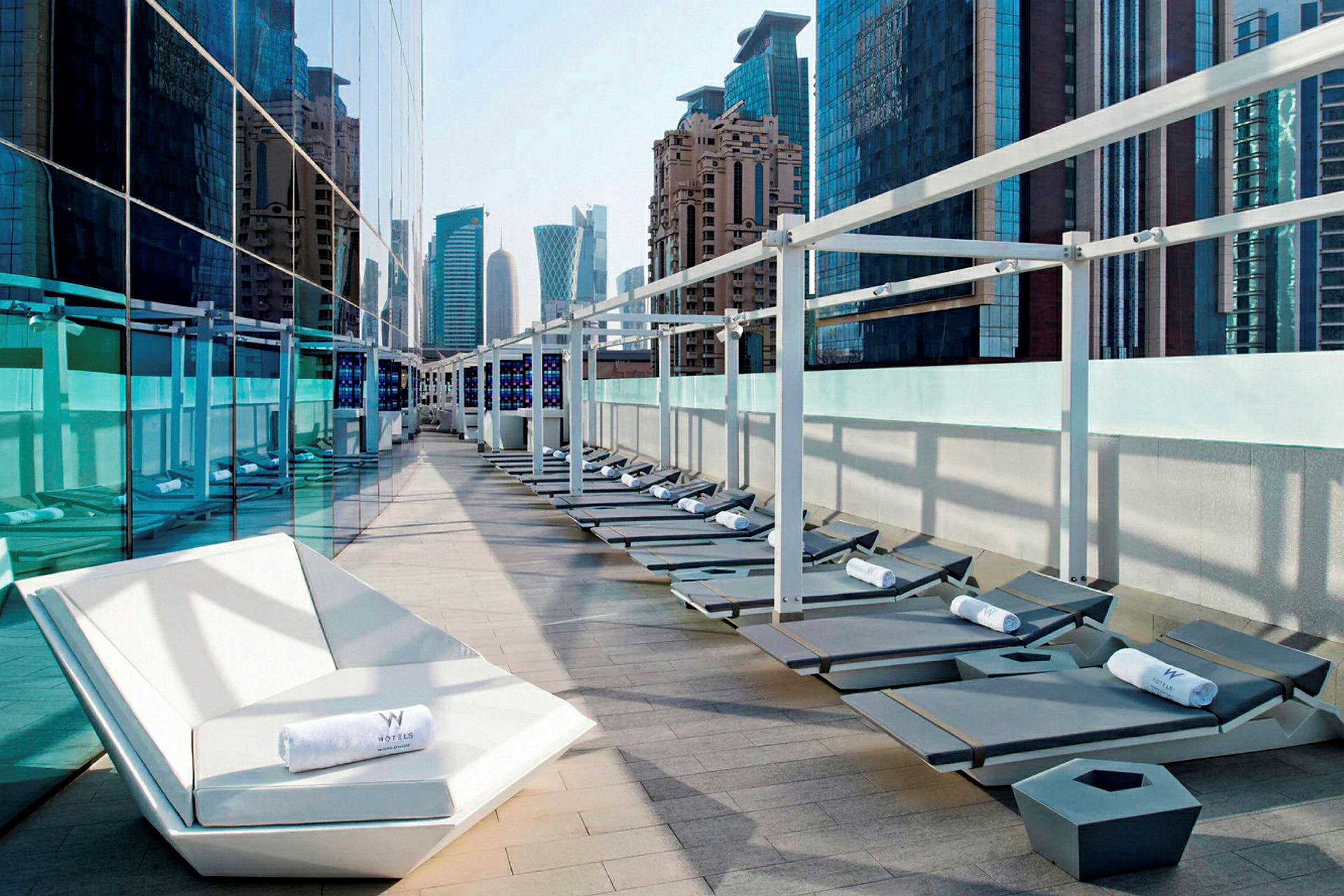 Solstolar och en lounge på en terrass med utsikt över moderna byggnader. (AI-genererad text)