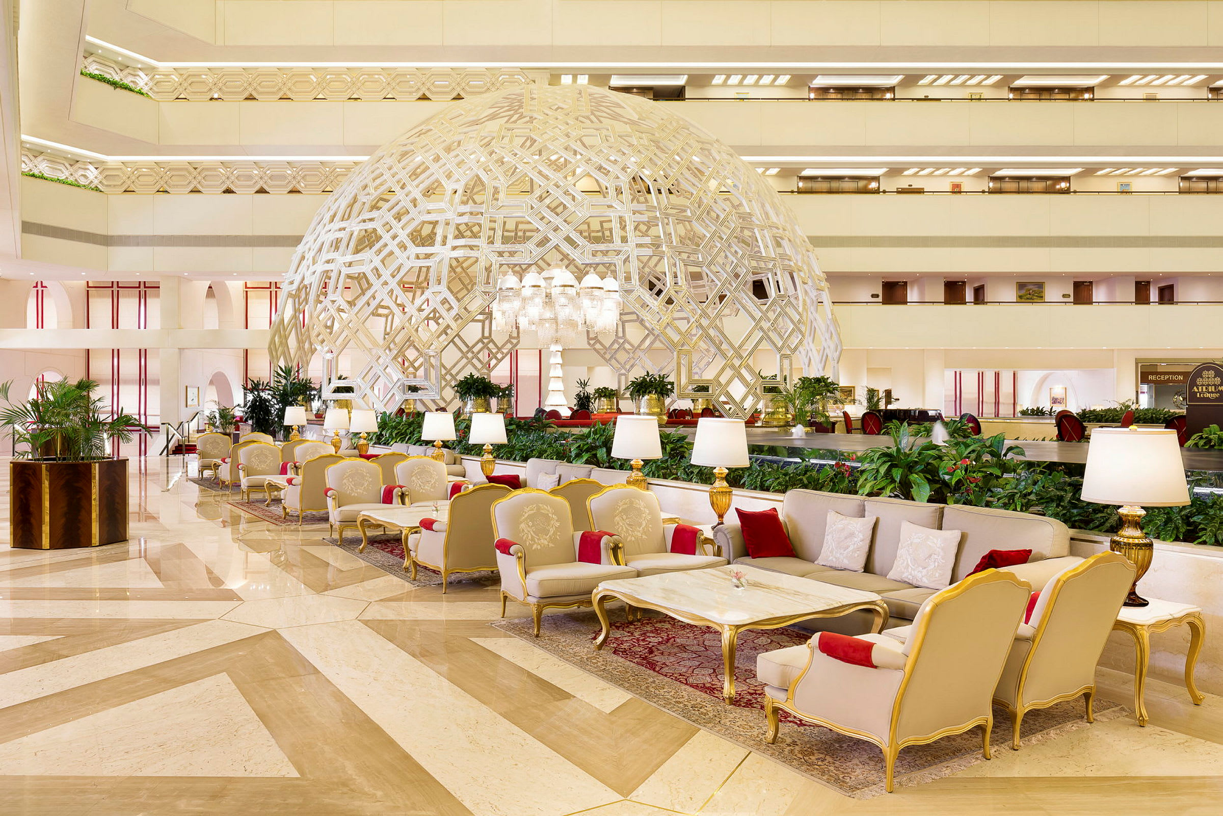 En elegant hotellobby med lyxiga sittplatser, en dekorativ geometrisk struktur och välskötta växter. (AI-genererad text)