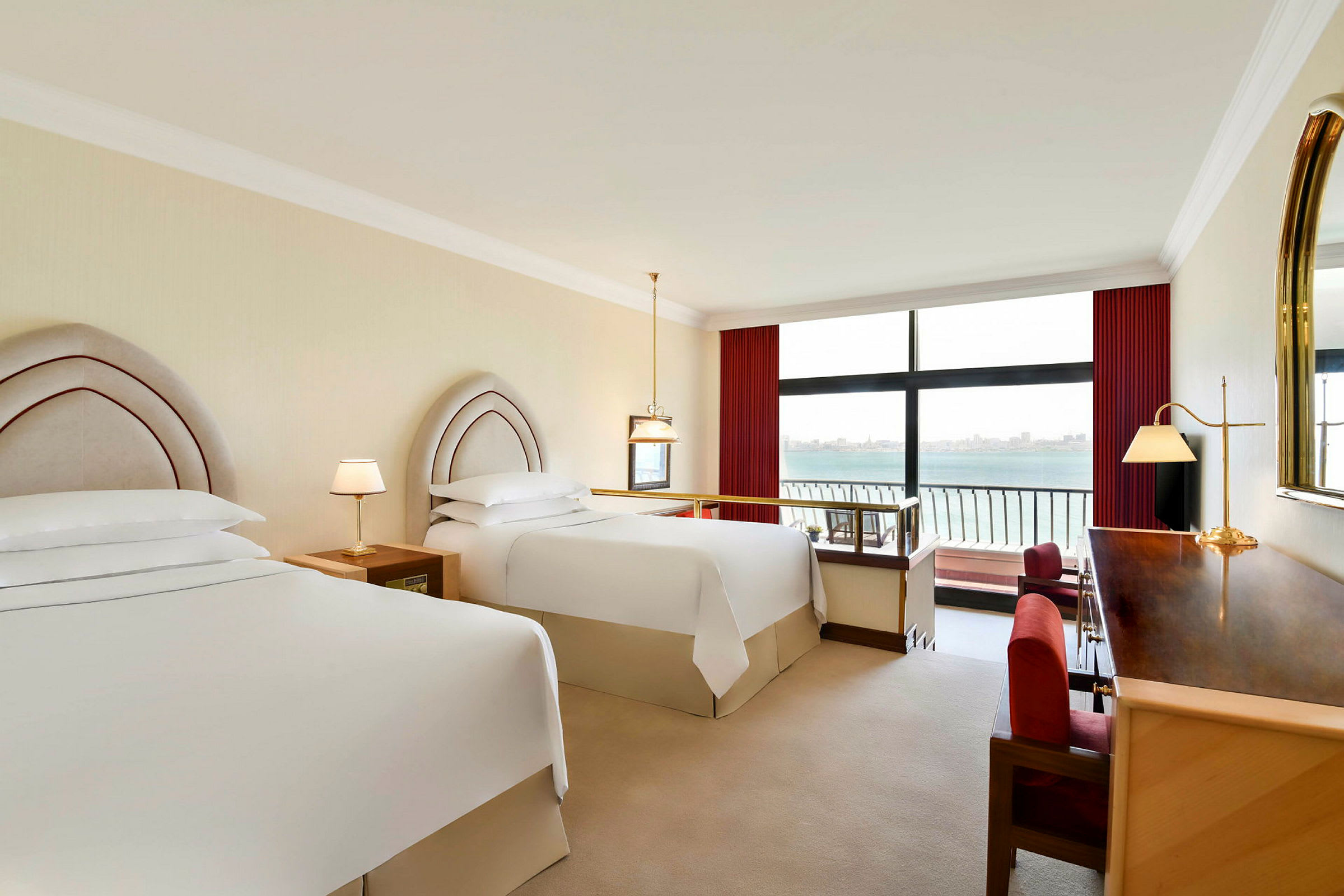 Hotellrum med två sängar bredvid ett stort fönster med utsikt över havet. (AI-genererad text)