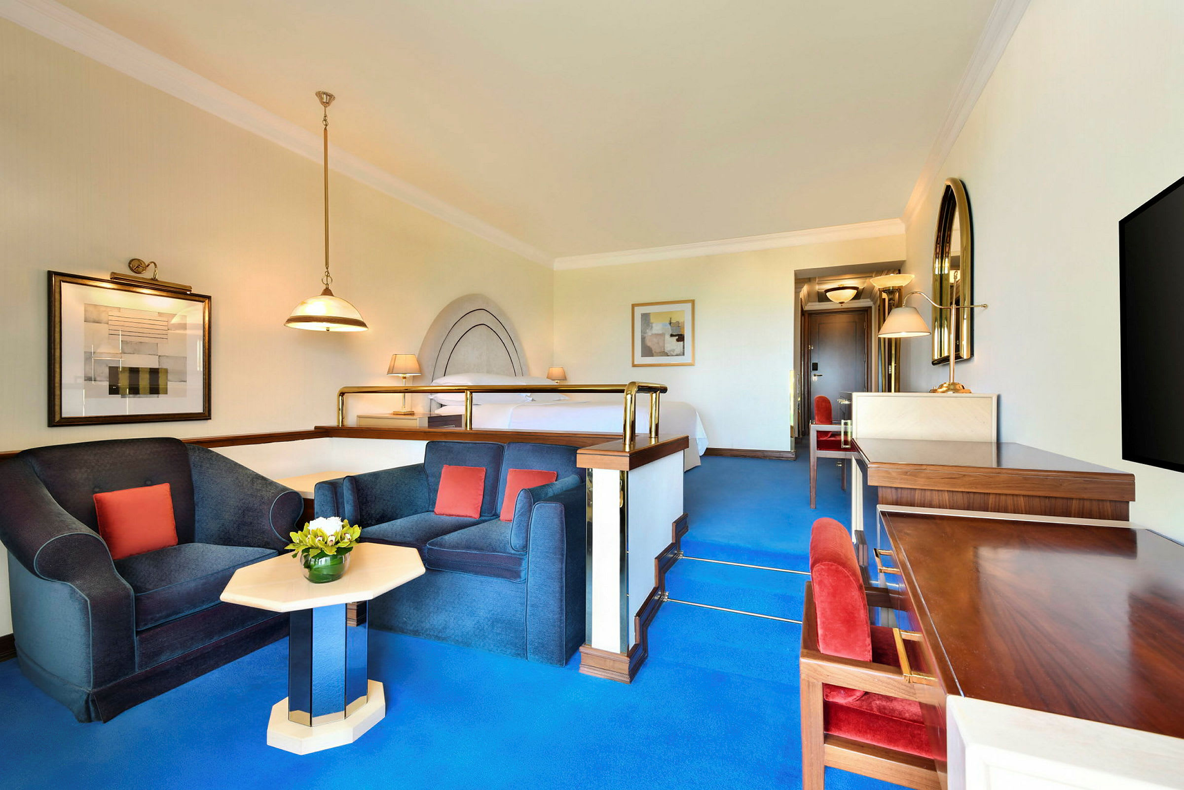 Ett välbelyst hotellrum med en upphöjd sängdel och en sittgrupp med två fåtöljer och ett litet bord. (AI-genererad text)