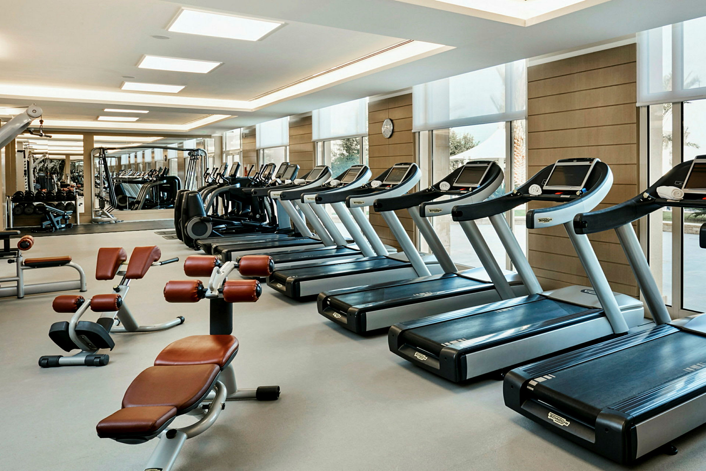 Ett modernt gym med träningsmaskiner och löpband placerade i ett ljust och rymligt rum. (AI-genererad text)