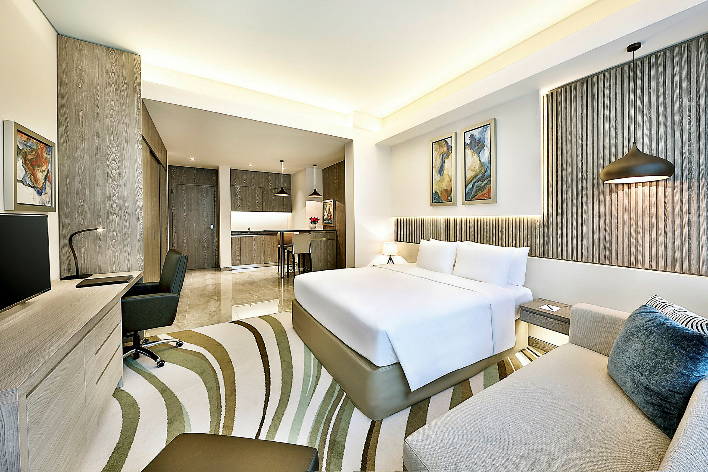 Modernt hotellrum med säng, soffa och skrivbord samt närhet till ett pentry. (AI-genererad text)