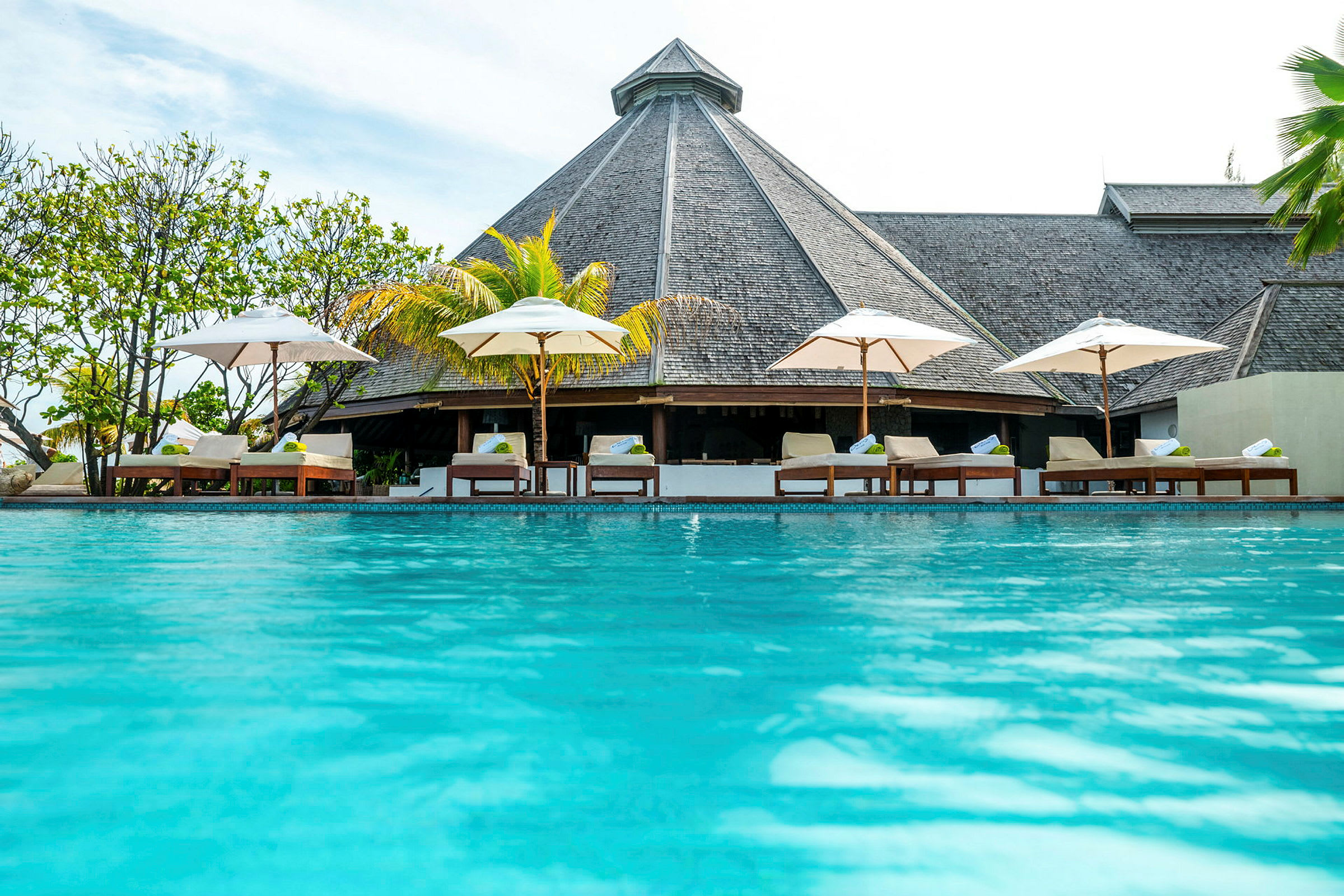 Utomhuspool vid ett semesterresort med solstolar och parasoller. (AI-genererad text)