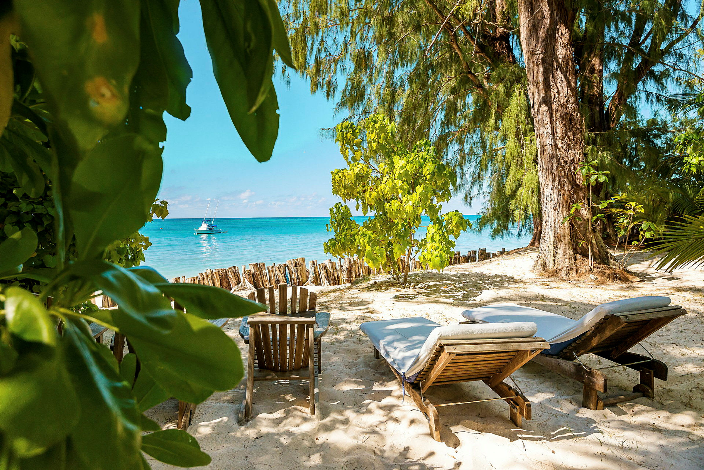 Två solstolar och en stol på en sandstrand med utsikt över havet. (AI-genererad text)