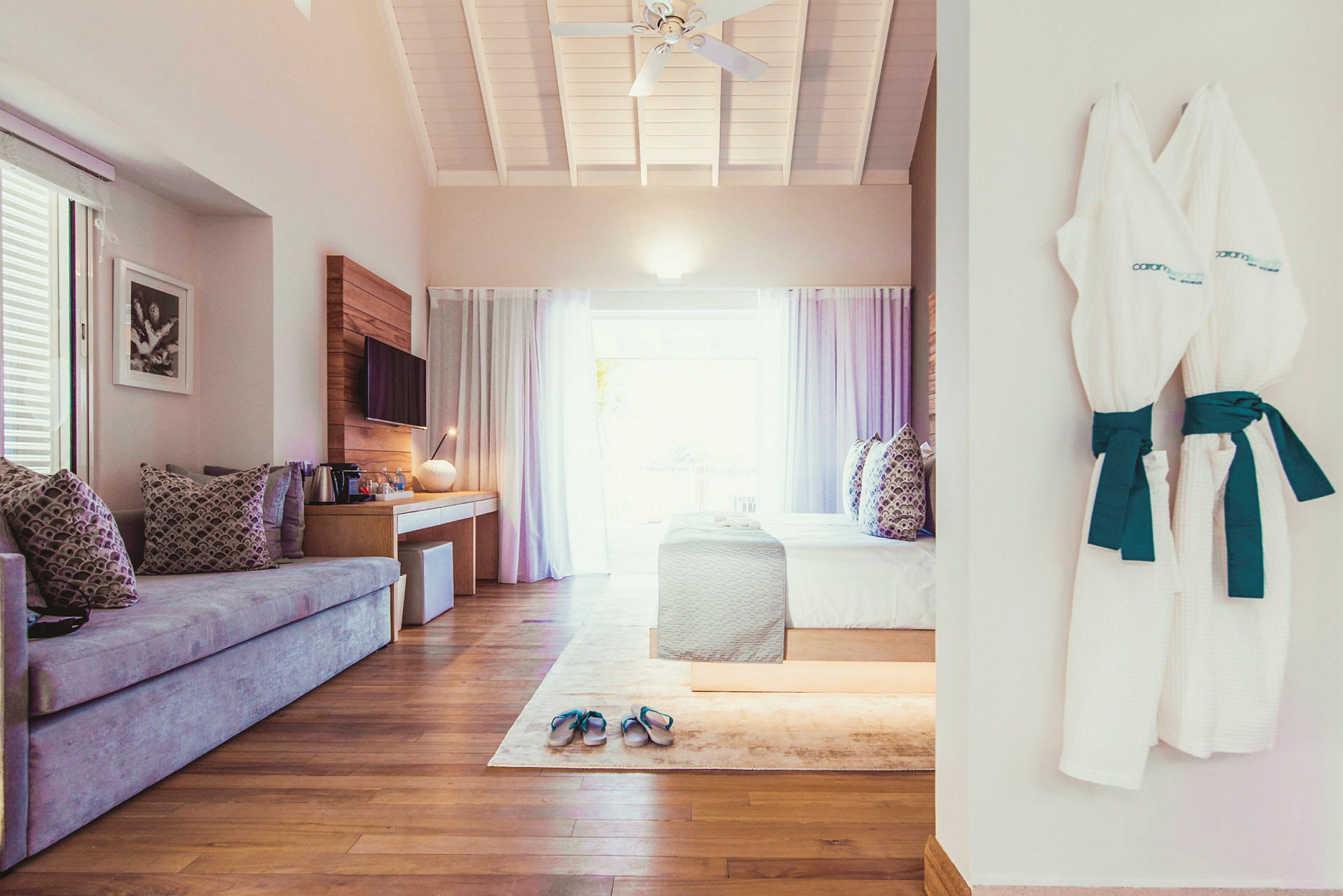 Ett hotellrum med soffa, säng, och badrockar hängande på väggen. (AI-genererad text)