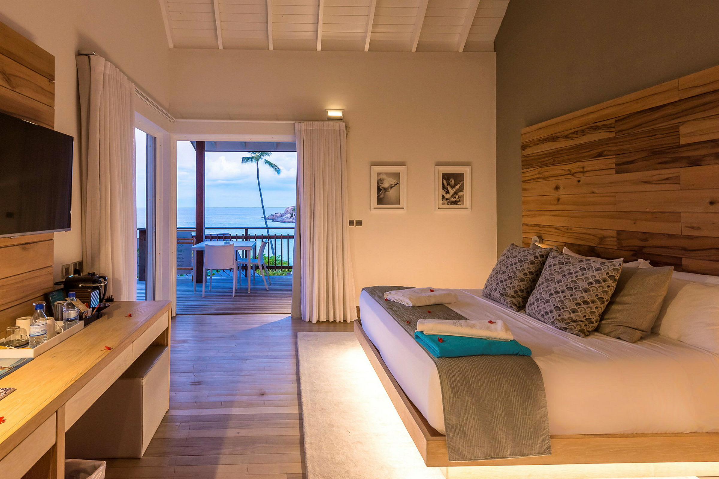 Ett hotellrum med en stor säng och utgång till en terrass med utsikt över havet. (AI-genererad text)