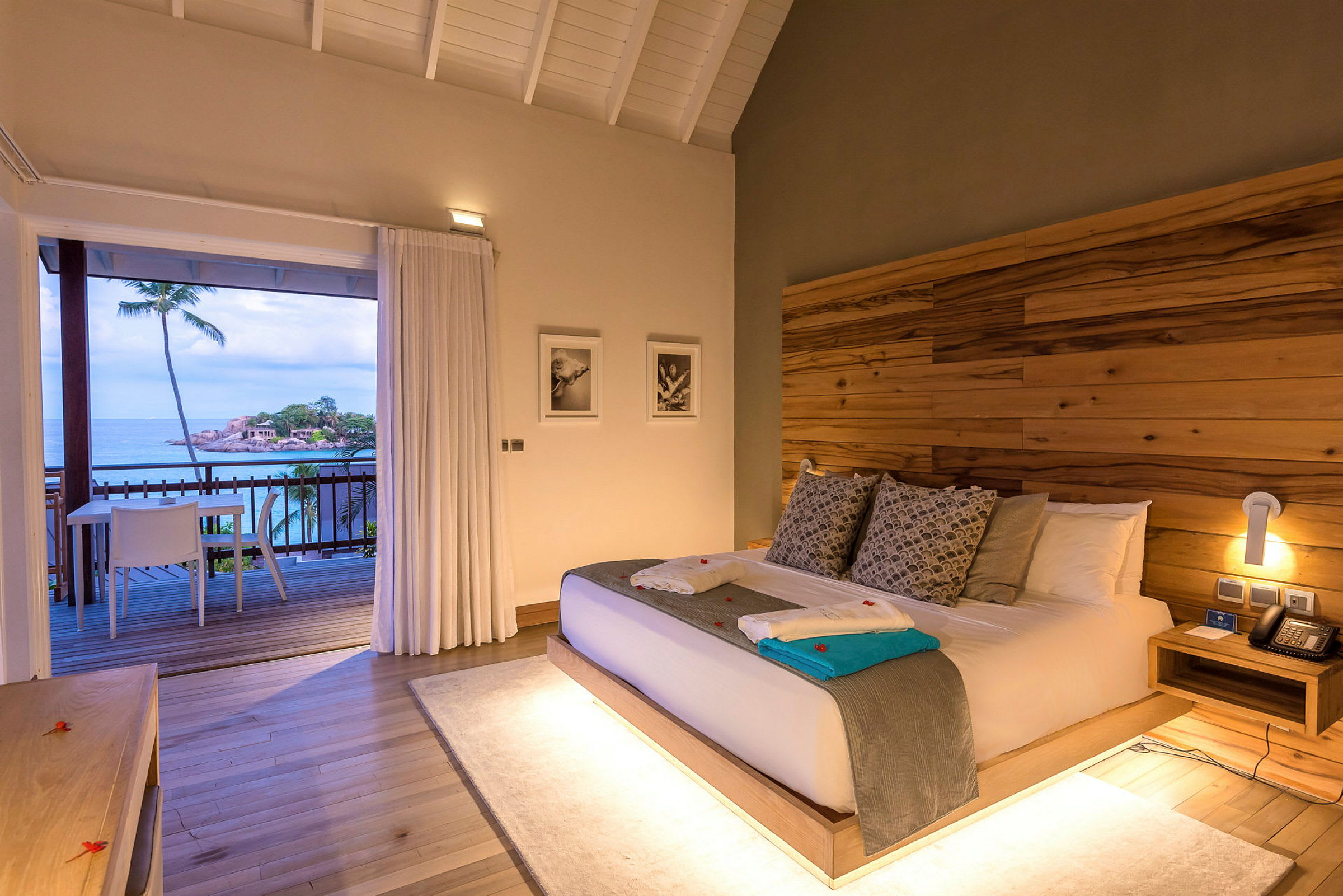 Hotellrum med en dubbelsäng och balkong som har utsikt över havet. (AI-genererad text)