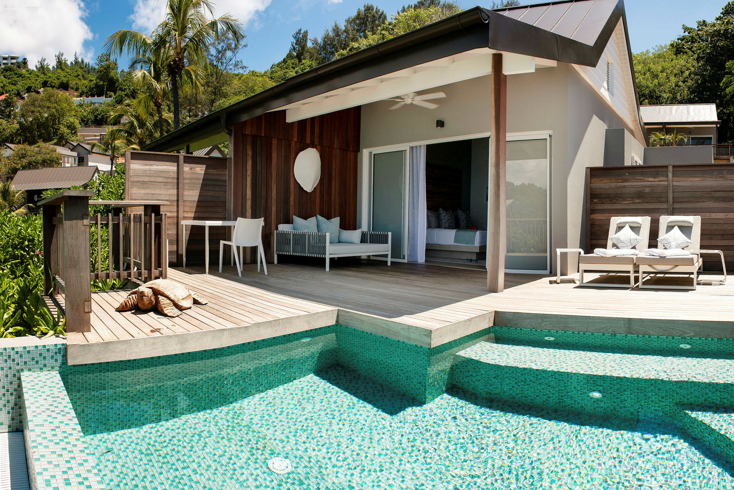 Modern bungalow med träterrass, solsängar och pool. (AI-genererad text)
