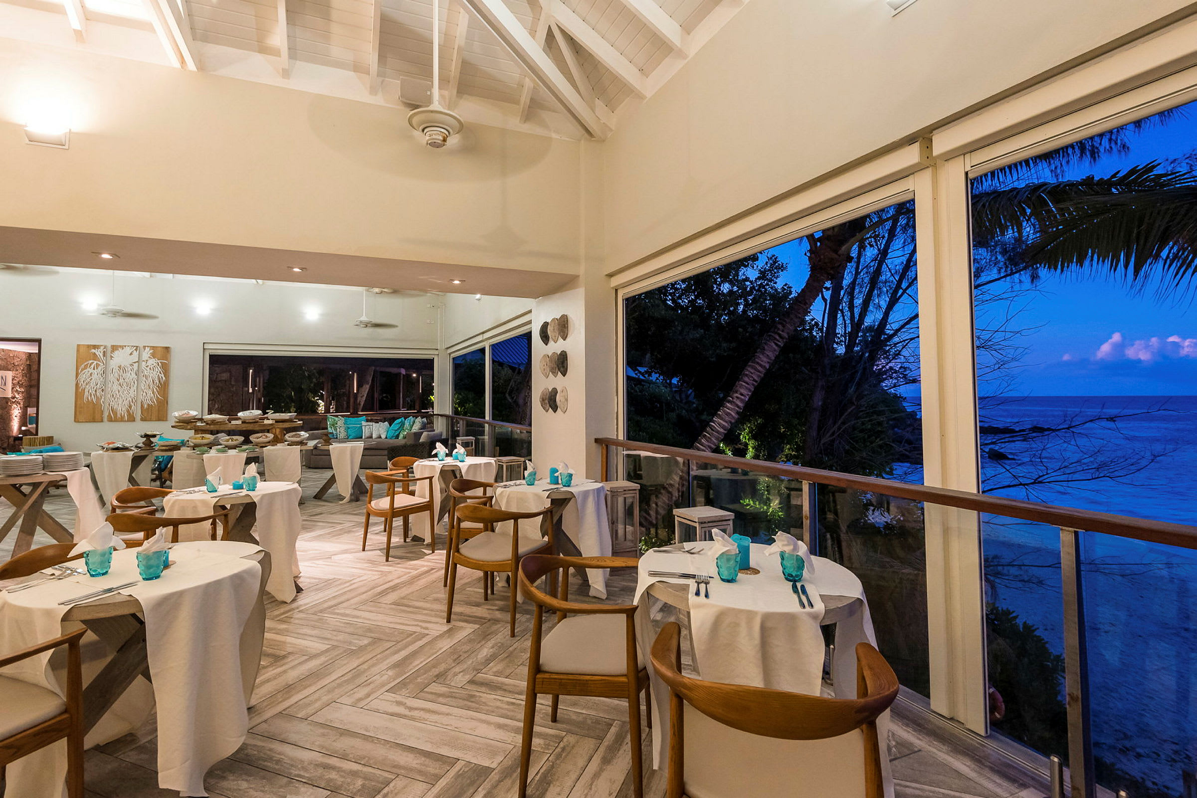 Ett restaurangområde med dukade bord och utsikt mot havet vid solnedgång. (AI-genererad text)