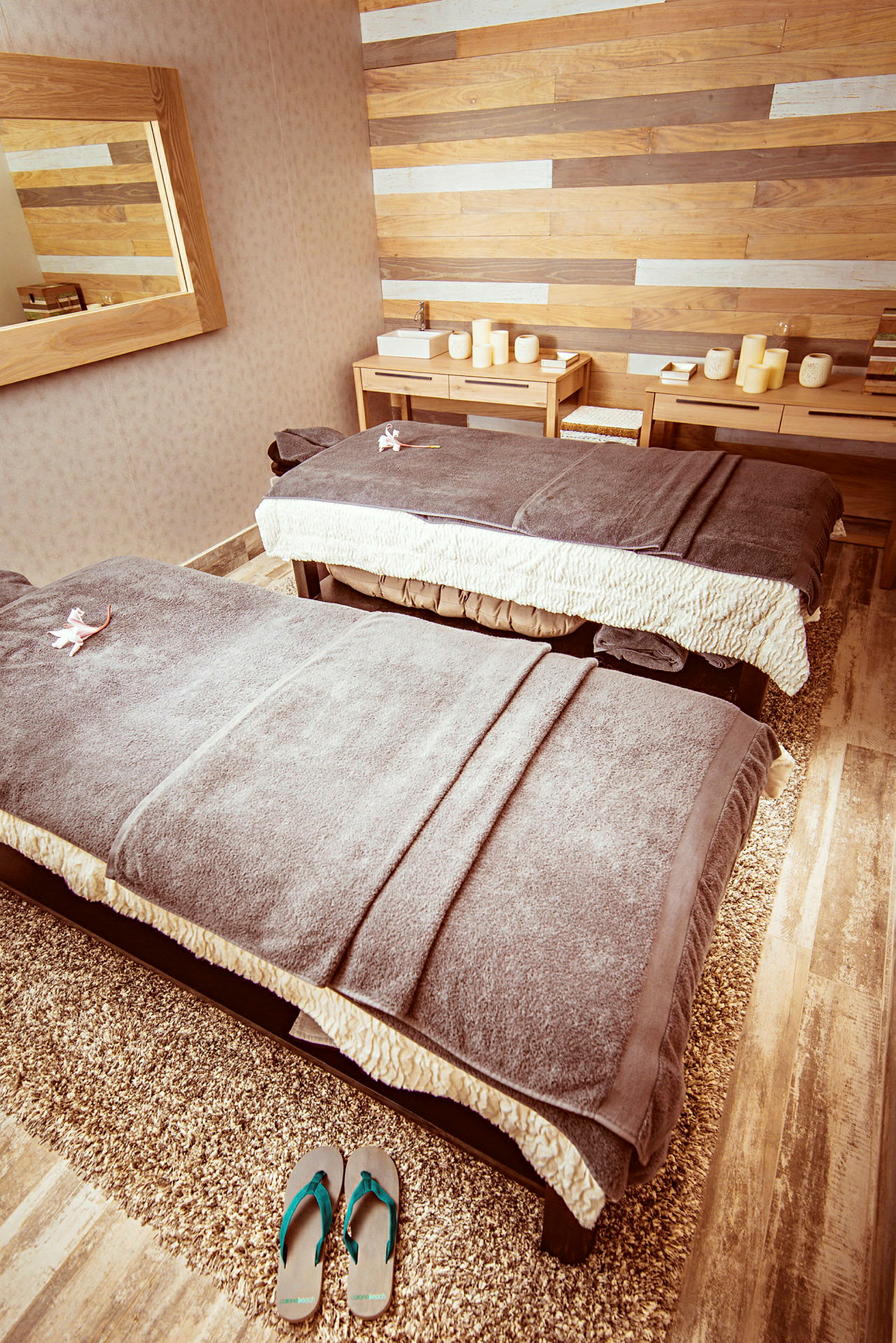 Två massagebänkar med handdukar i ett rum med träpanelväggar och relaxmiljö. (AI-genererad text)