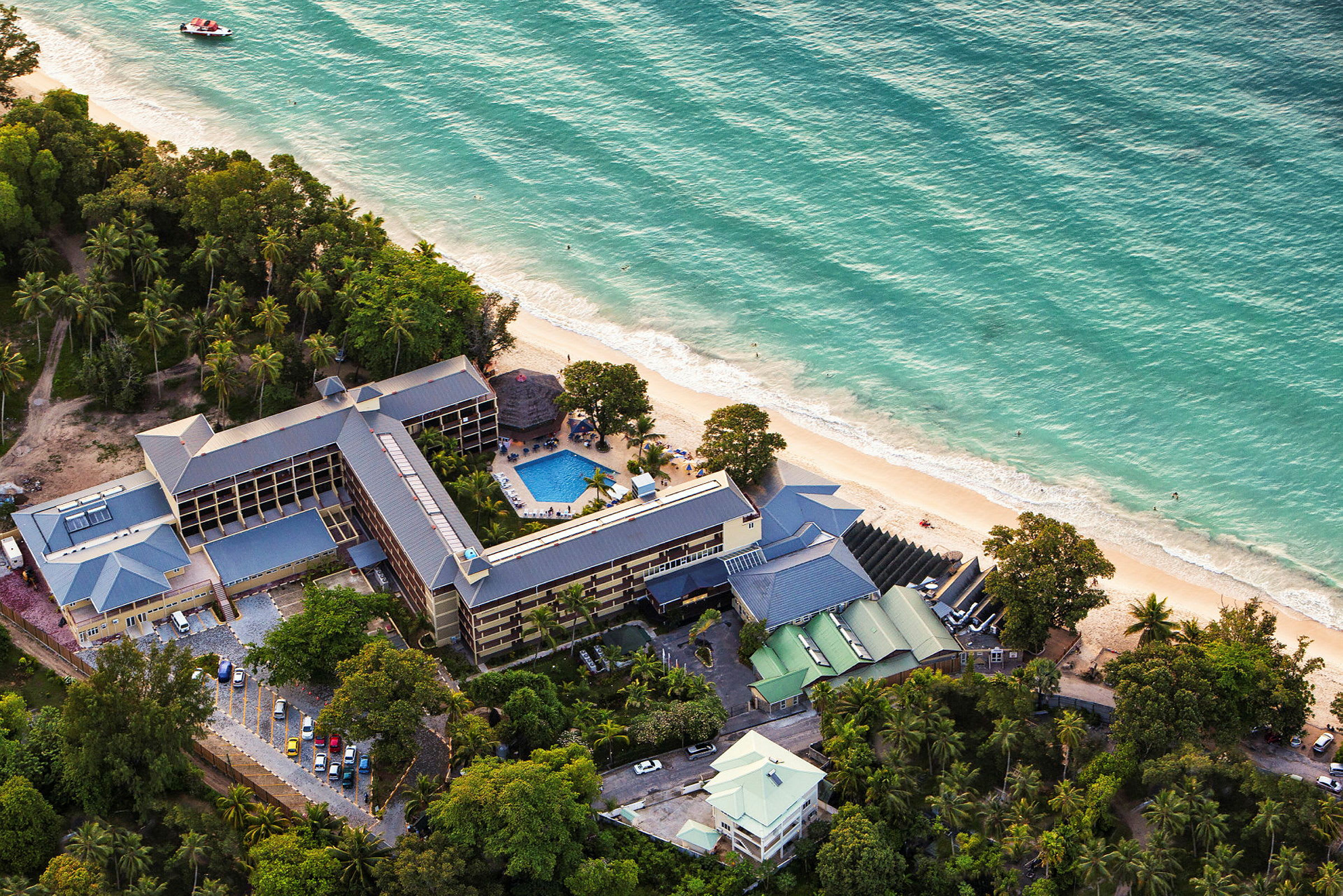 Flygfoto av hotell med tillhörande poolområde vid stranden. (AI-genererad text)
