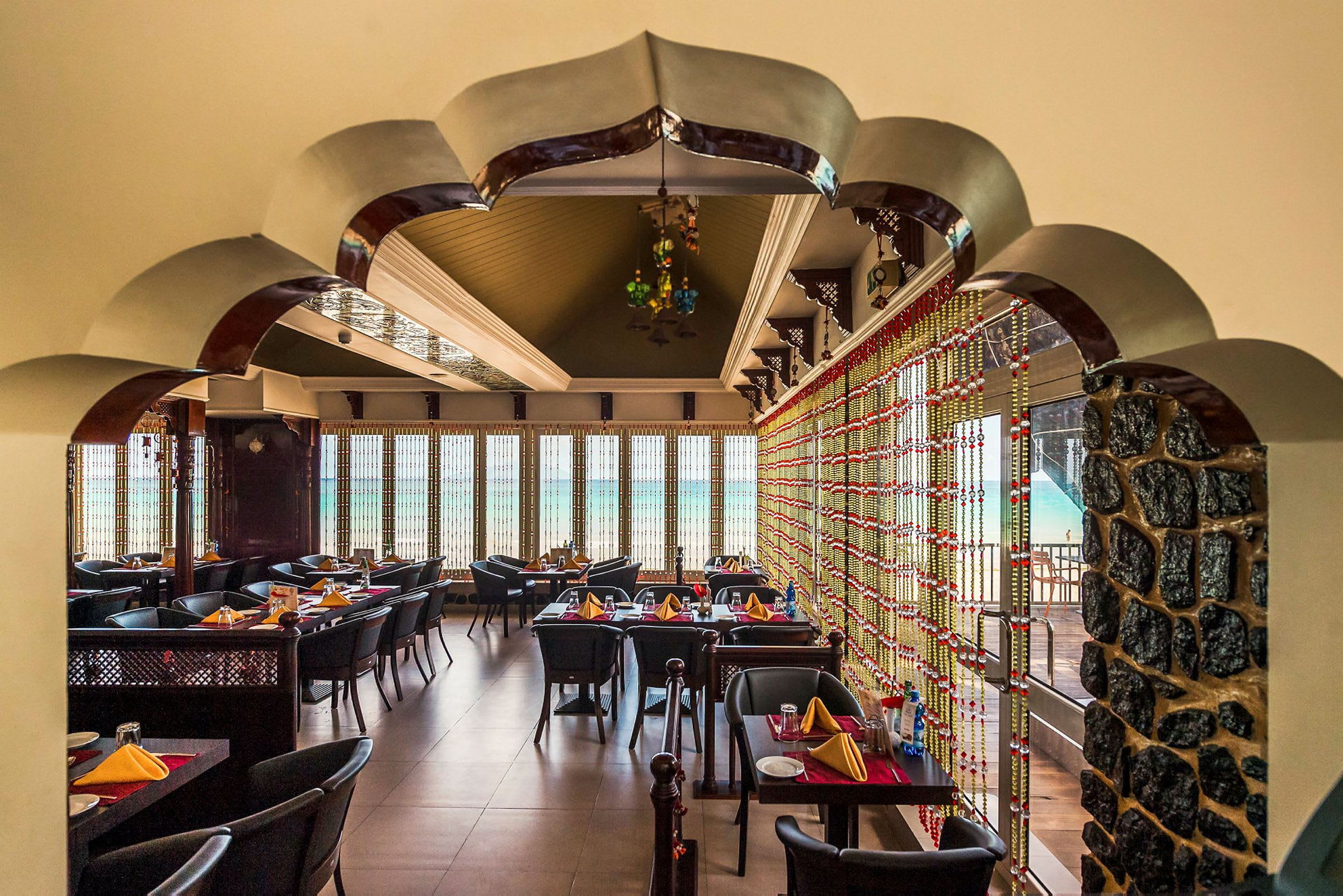 Ett smakfullt inrett restaurangområde med bordsplaceringar och dekorativa detaljer, som en fönstervägg som blickar ut mot utsikten. (AI-genererad text)