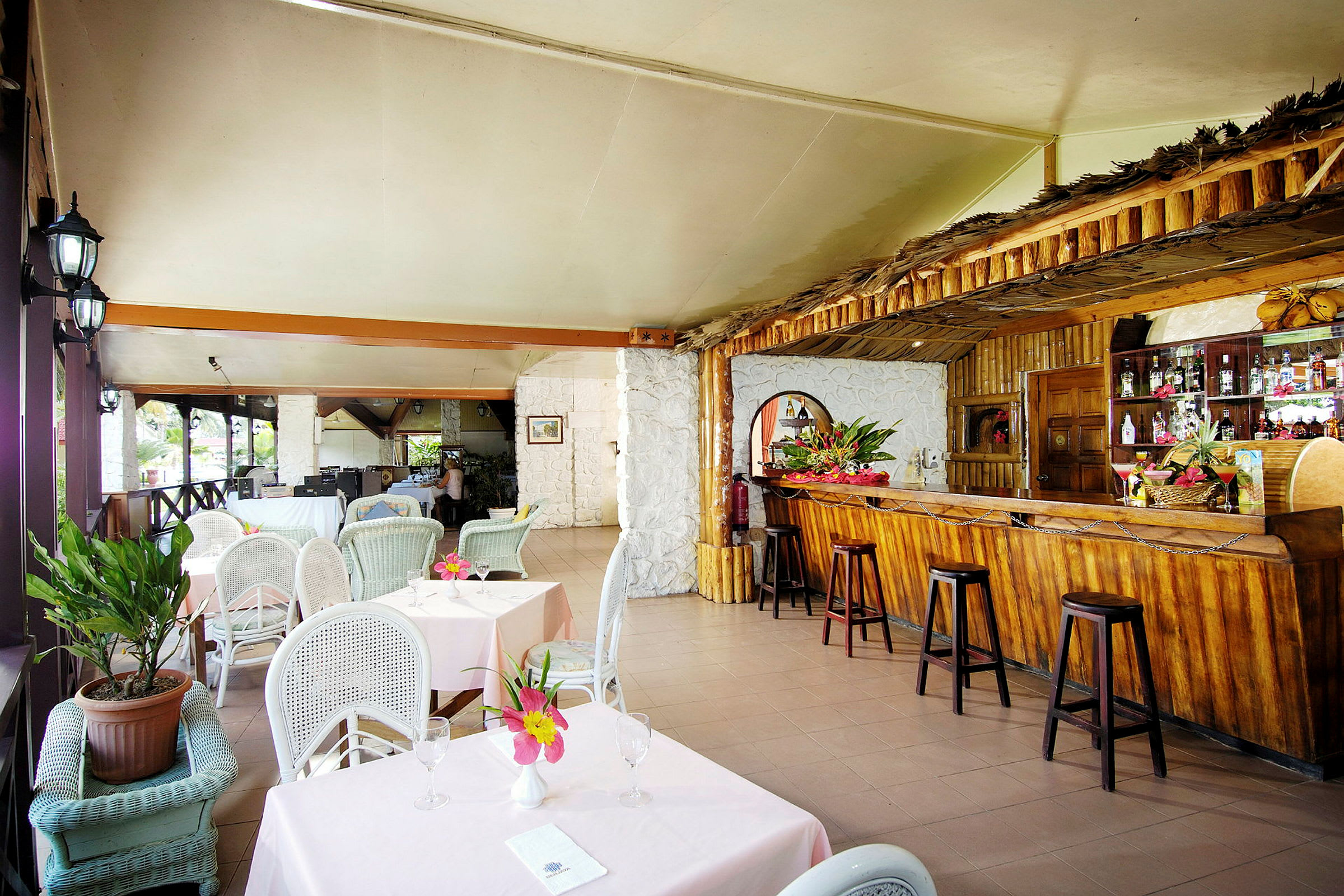 En restaurang med sittplatser uppställda och en träbar med dekorationer. (AI-genererad text)