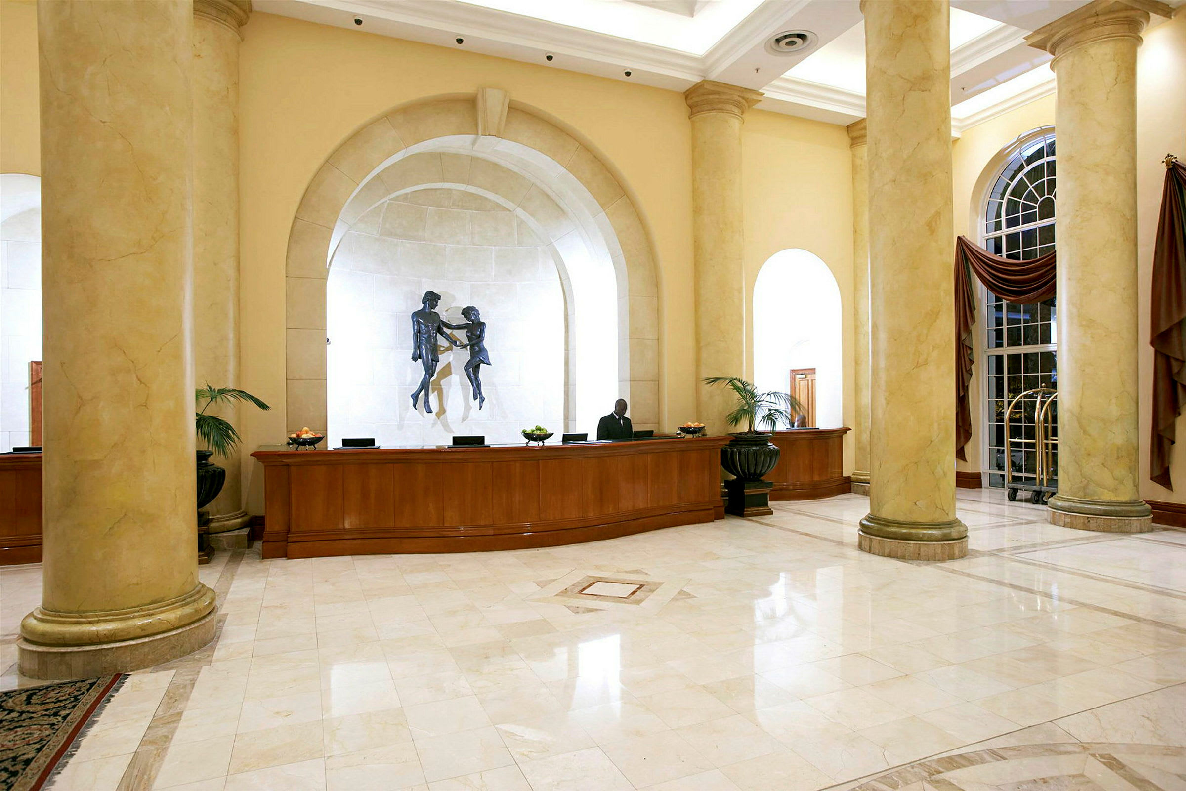 Hotellobby med receptionsdisk, pelare och väggprydnad. (AI-genererad text)