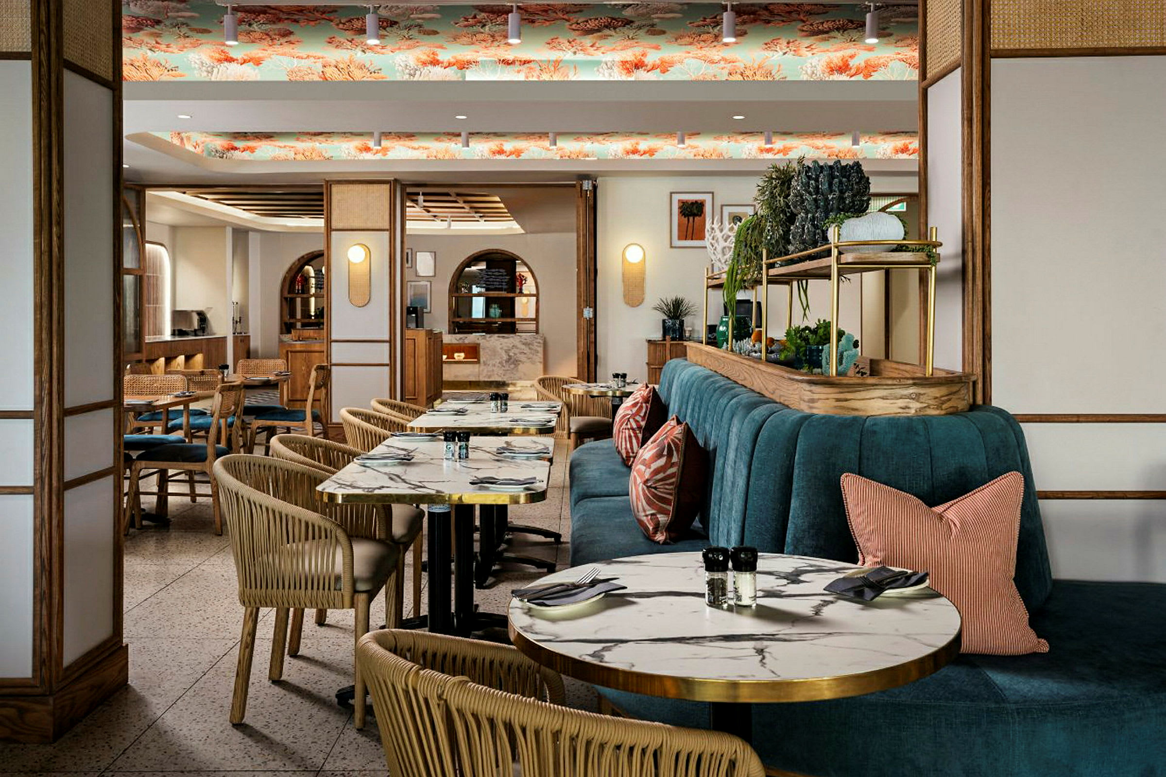 En restauranginteriör med marmorerade bord, rottingstolar och en turkos sittbänk med kuddar. Taket har dekorativt mönster. (AI-genererad text)