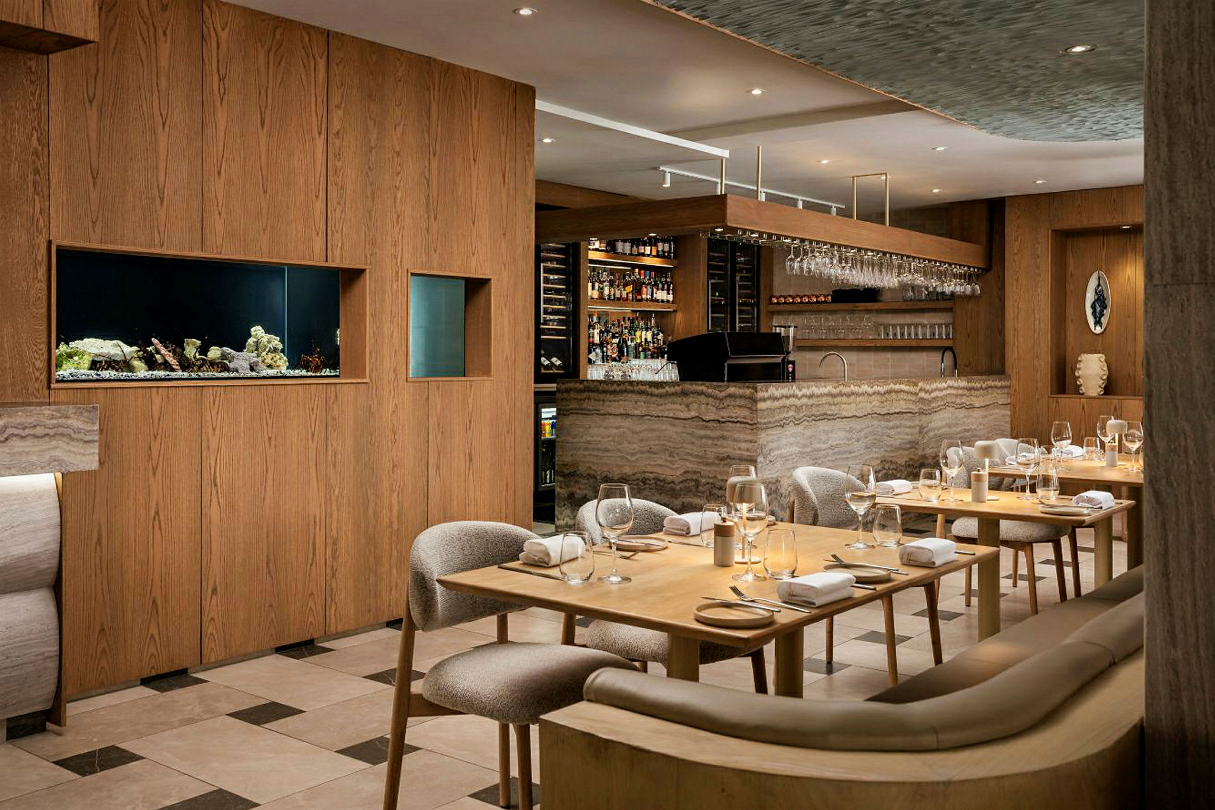Ett elegant restauranginteriör med trämöbler och en bar i marmordesign. Bord är dukade med glas och servetter. (AI-genererad text)