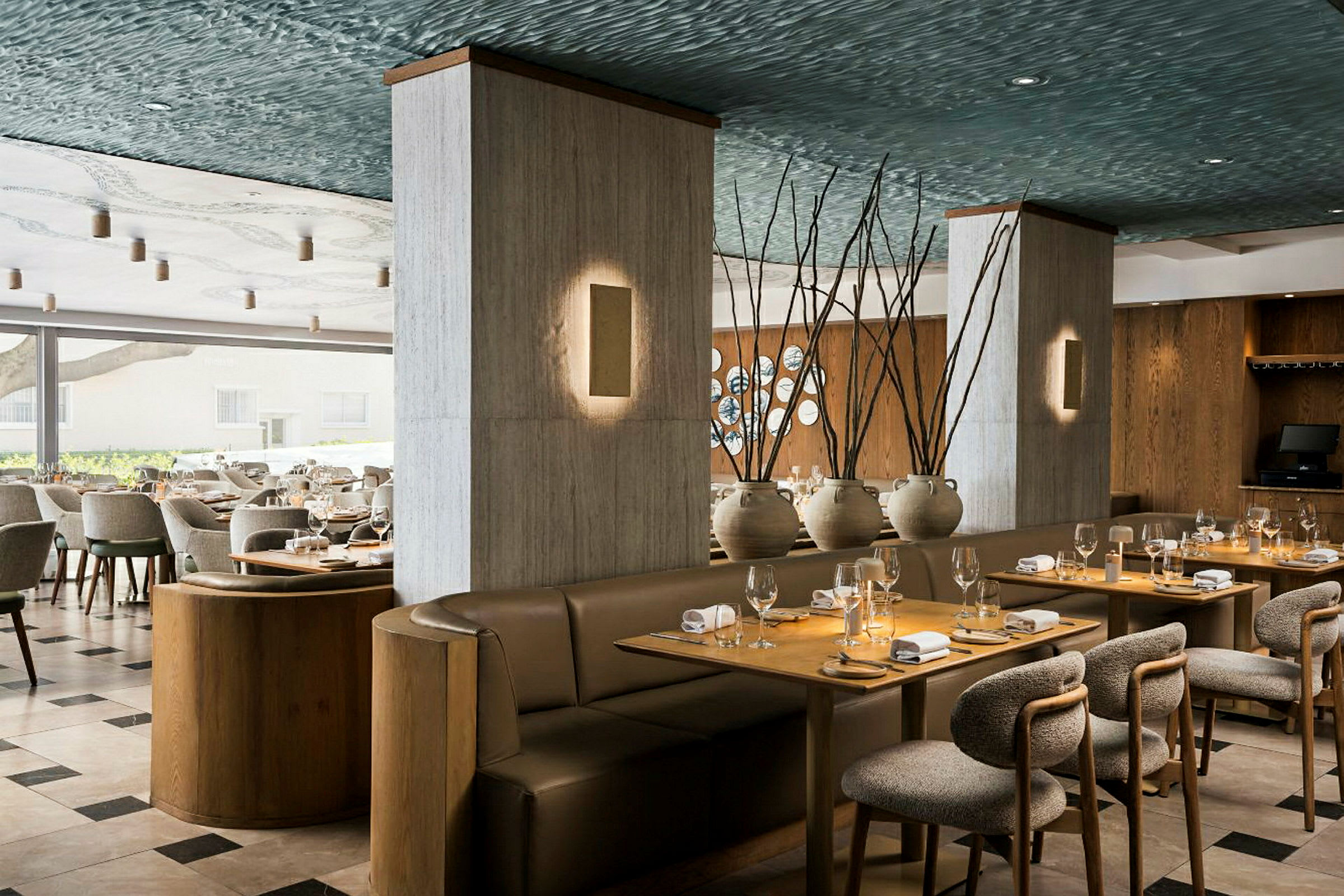 En elegant restauranginteriör med dukade bord, vadderade stolar och mysiga soffor. Dekorationer inkluderar keramikvaser och trädetaljer. (AI-genererad text)