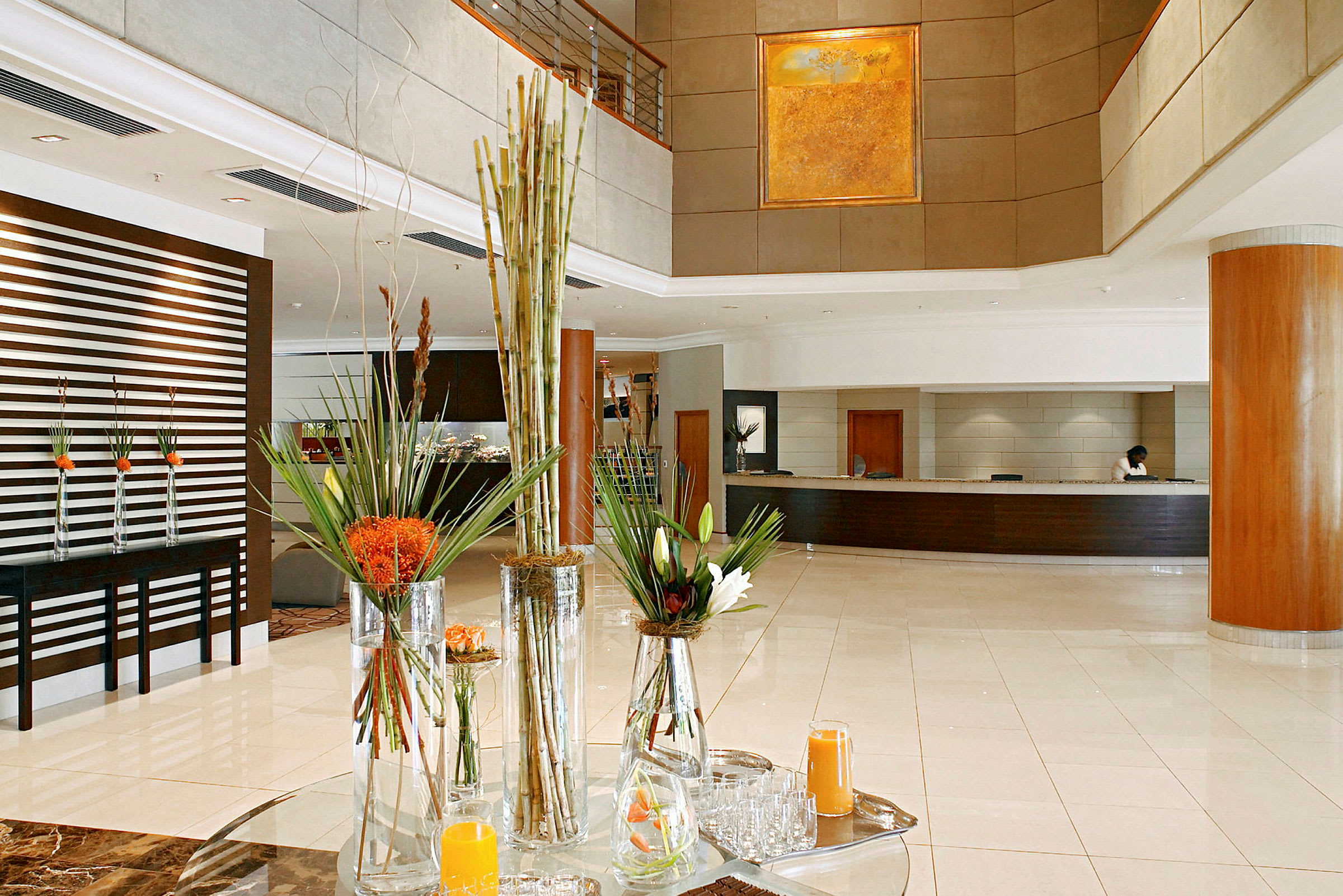 Ljus och stilren hotellobby med reception och blomsterarrangemang. (AI-genererad text)