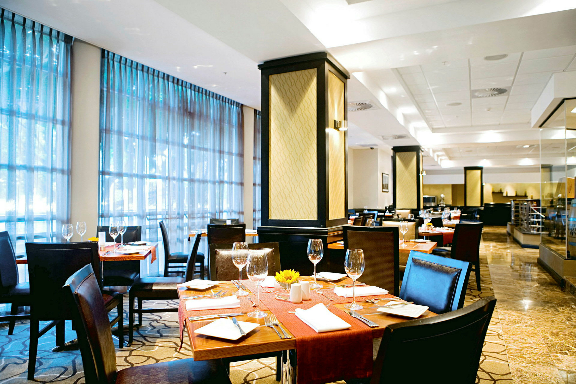 Ett elegant inrett restaurangområde med bord som är dukade med glas och bestick. (AI-genererad text)