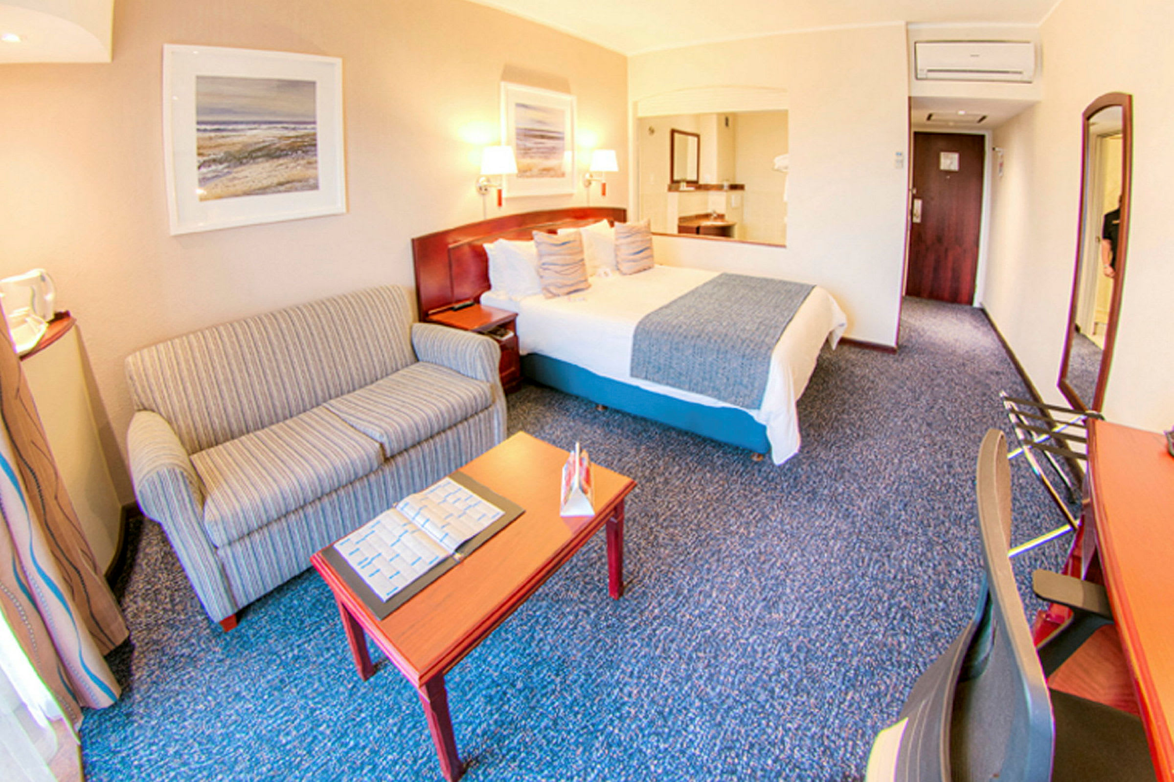 Ett hotellrum med en säng, en soffa, ett bord och en arbetsplats. (AI-genererad text)
