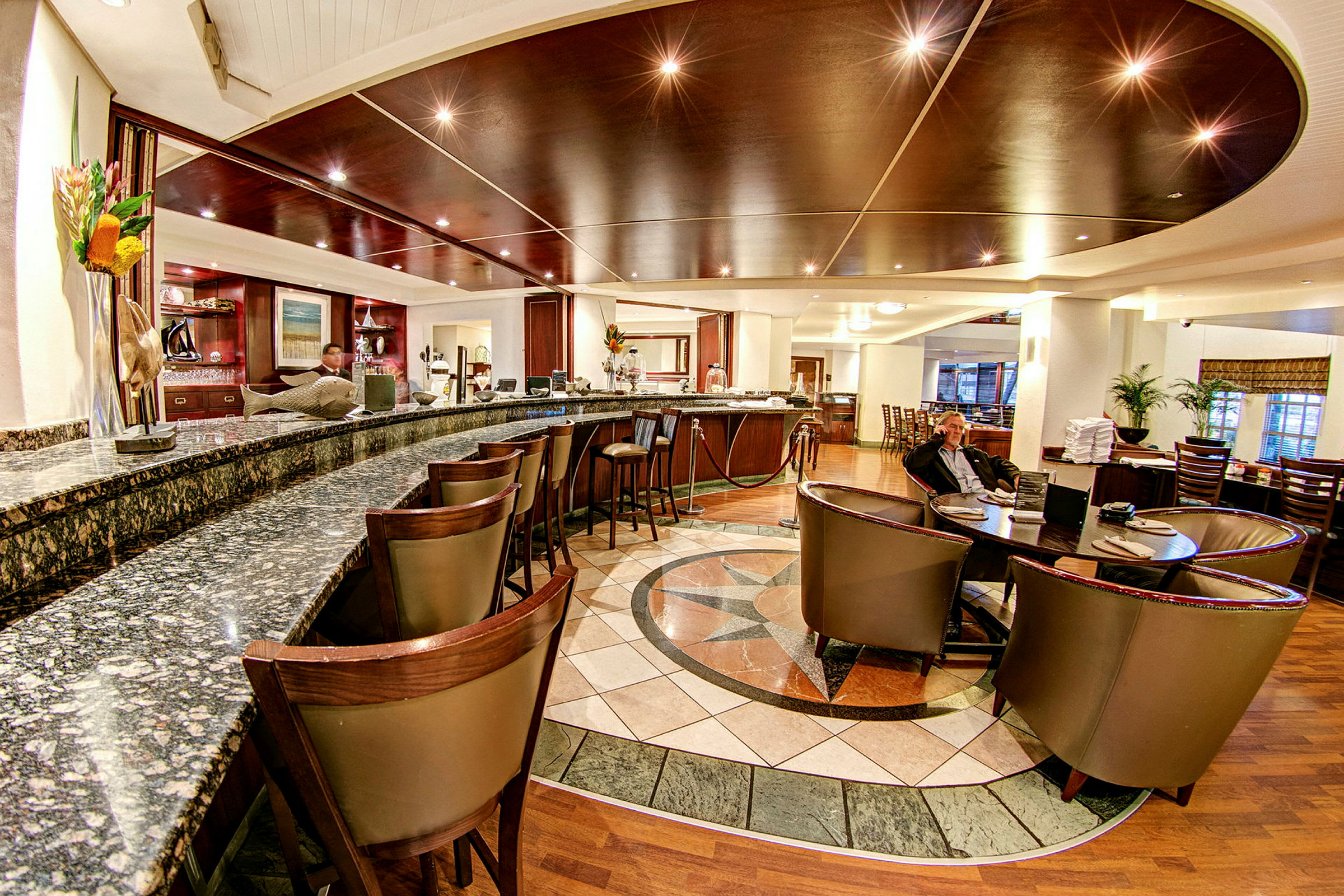 Ett elegant hotellbarområde med marmorbardisk, mörka trämöbler och loungeområde. (AI-genererad text)