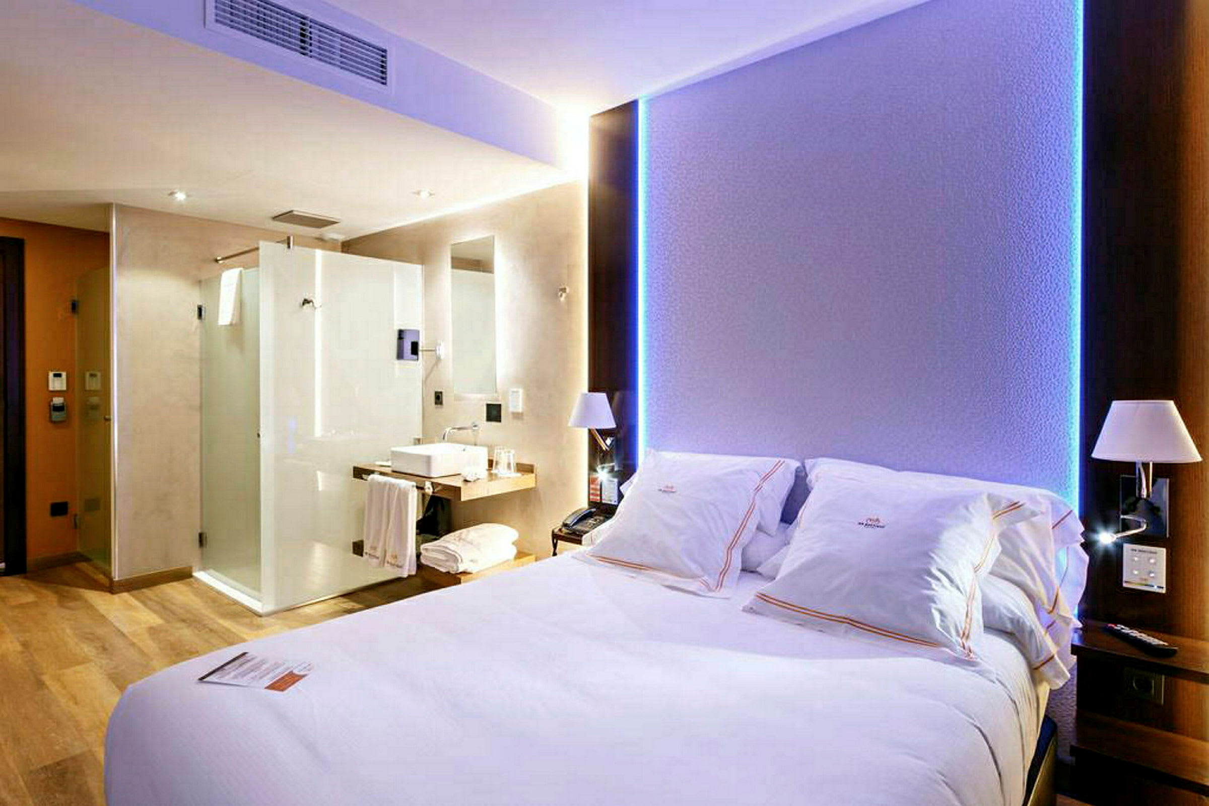 Ett hotellrum med en stor säng, ljus inredning och synliga badrumsfaciliteter. (AI-genererad text)