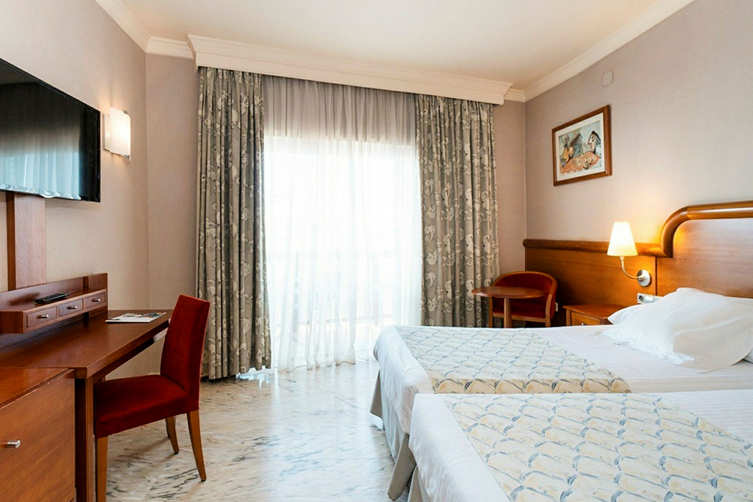 Ett hotellrum med två enkelsängar, ett skrivbord med en stol och en TV på väggen. (AI-genererad text)