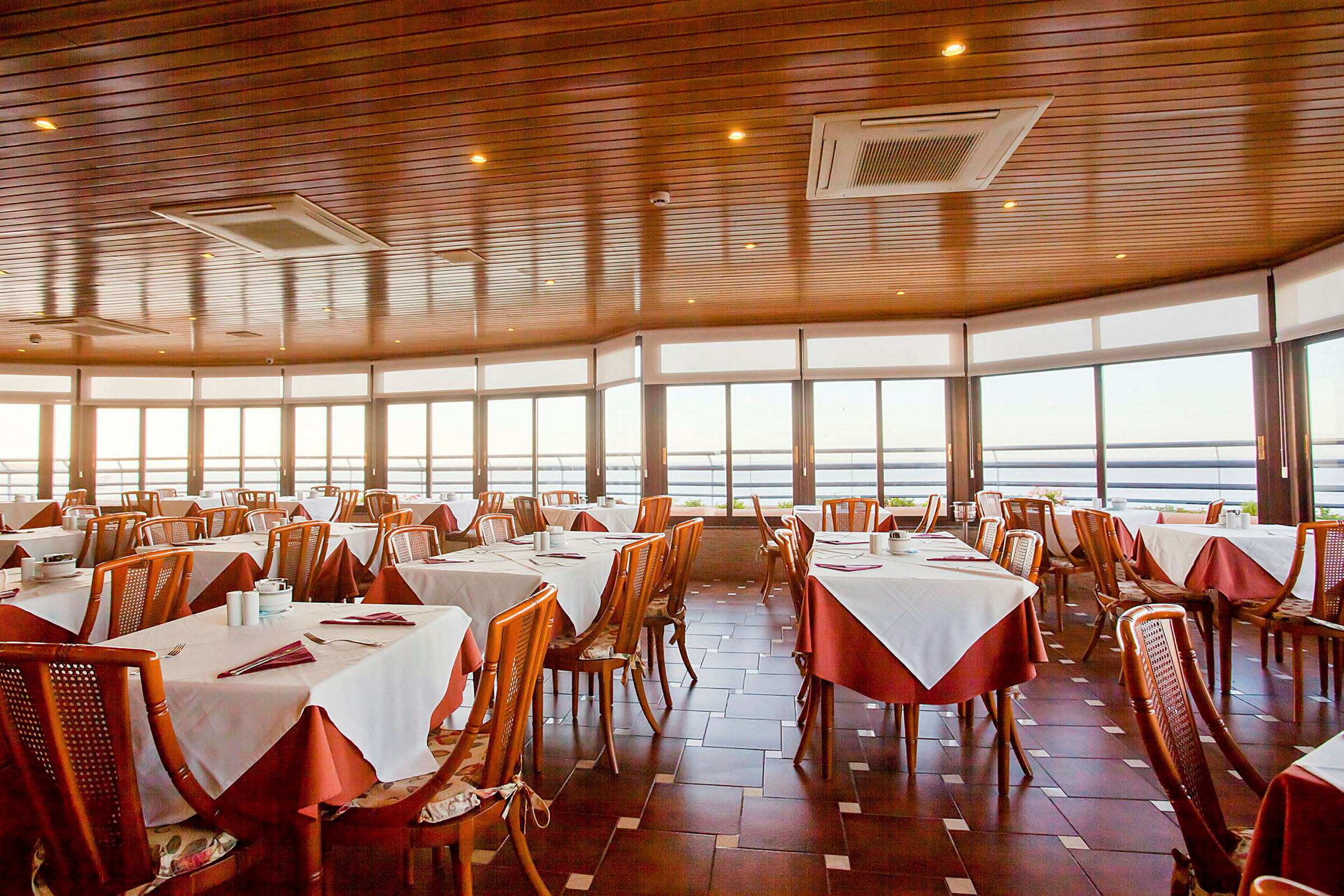 En restaurang med dukade bord och stora fönster med utsikt. (AI-genererad text)