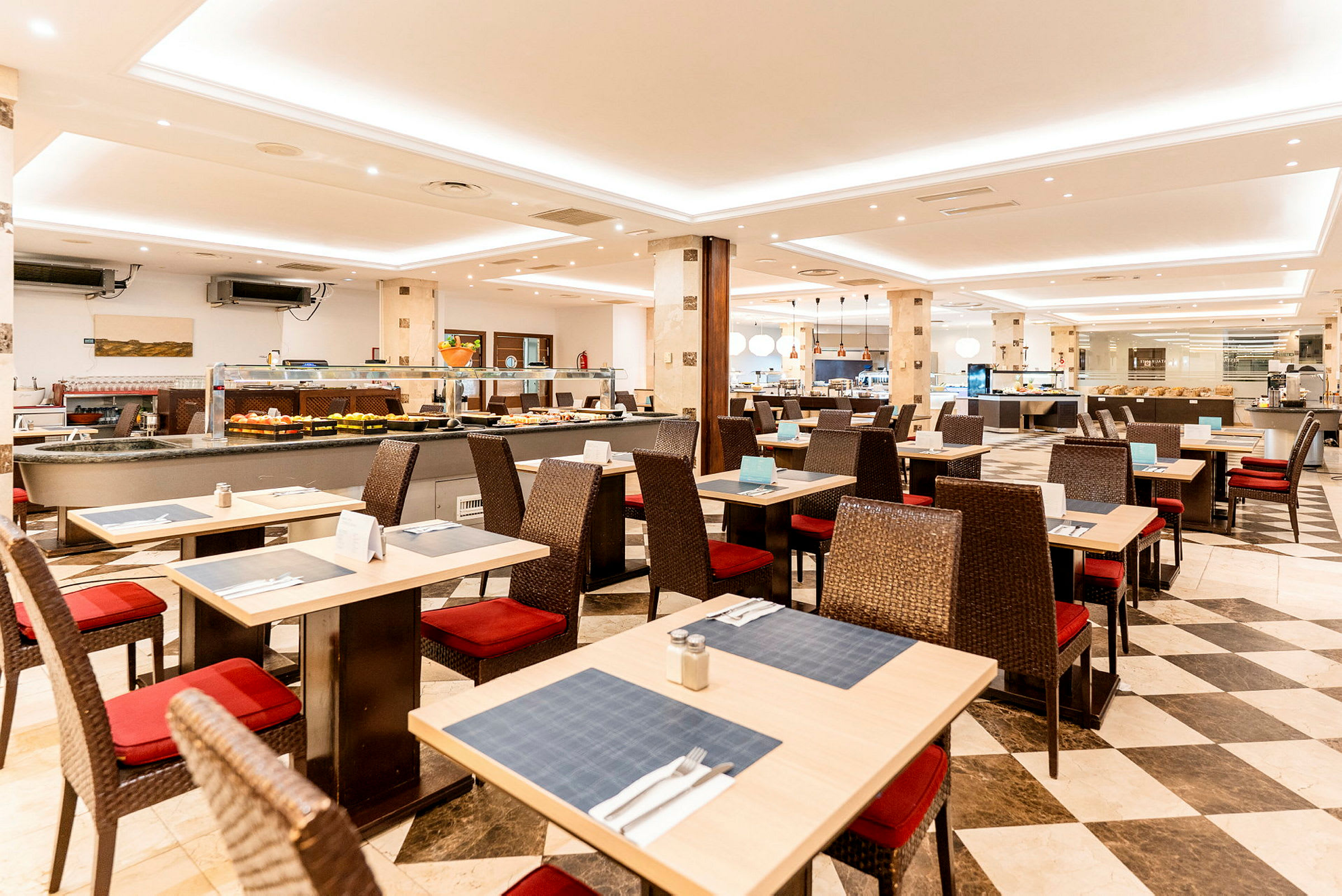 Bild av en restaurang med dukade bord och stolar, samt en buffé i bakgrunden. (AI-genererad text)